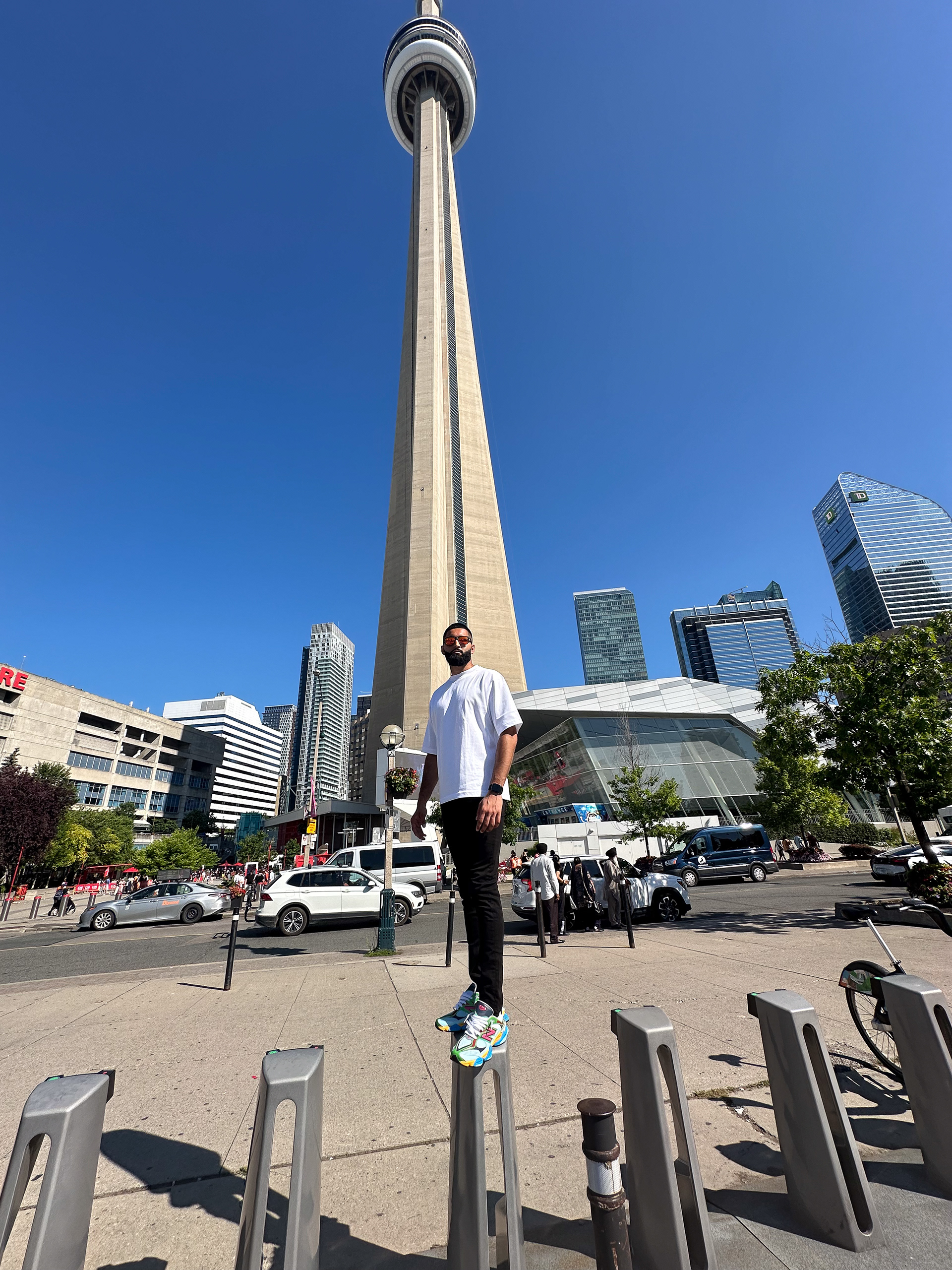 Muhammad Abbasi | Lifestyle | White oversized t-shirt, black jeans, colorful sneakers, standing in front of CN Tower
