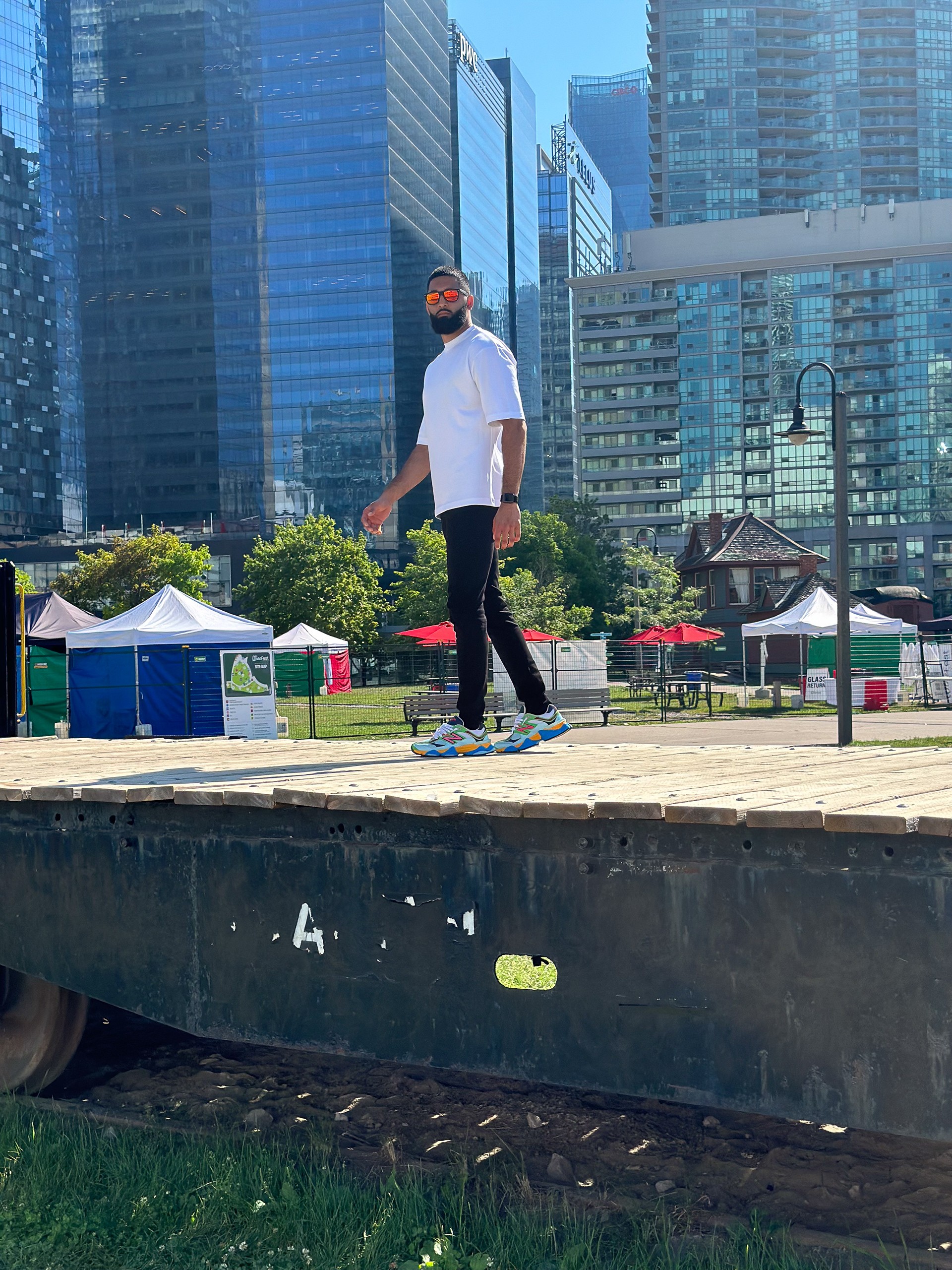 Muhammad Abbasi | Lifestyle | White oversized t-shirt, black jeans, colorful sneakers, side view on wooden dock in Toronto