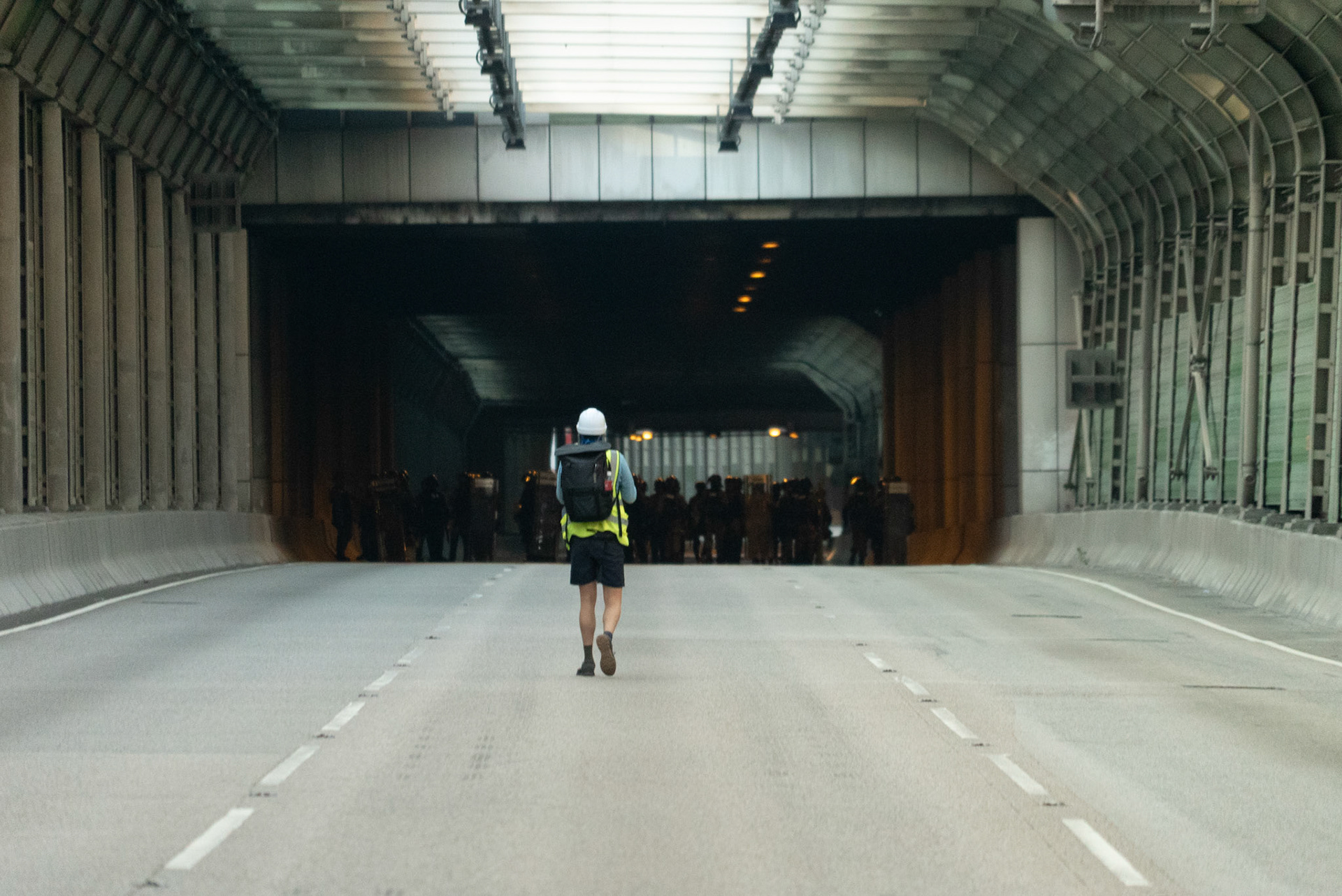 A journalist approaches an advancing police patrol clearing a highway of protesters in Tuen Mun.Since the start of the Hong Kong protests in June 2019, there has been a large cohort of journalists present on the ground. Often wearing yellow vests and carrying gas masks and cameras, the press soon became and integral wall of observers at the frontlines. The police have accused many of not representing legitimate media organizations, of adding to the numbers, and of getting in the way of police operations. The protesters have generally welcomed media presence, often calling for them to come forward during arrests and other police actions.21/09/2019, Tuen Mun, Hong Kong SAR.