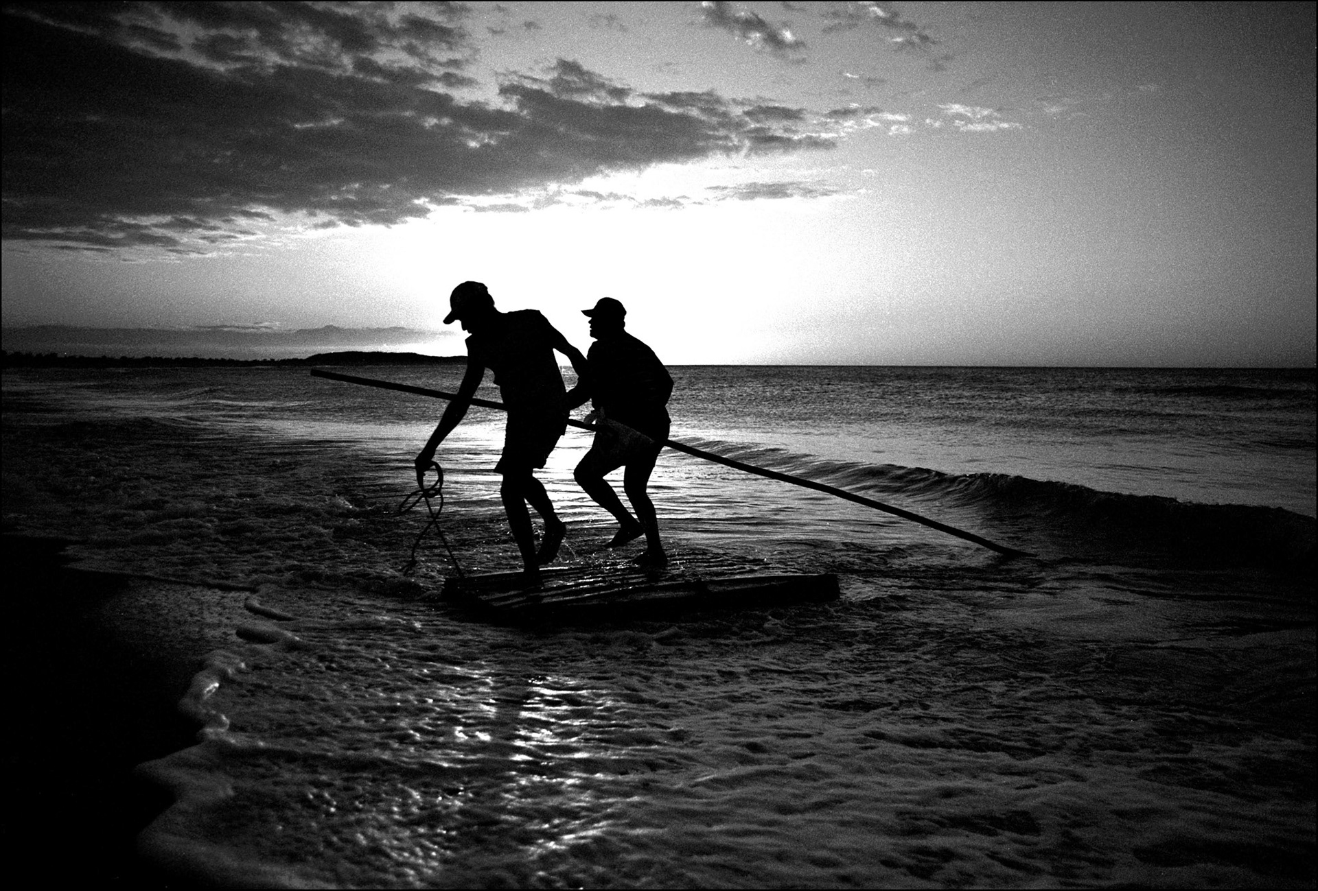 Two fishermen arrive back at sunset. Galinhos is a small oceanside village in the far north of Brazil. Poised on a thin peninsular it can only be reached by a small fishing boat or by walking over the sand dunes that guard it from the mainland. The people make their living from the sea that surrounds them, and the few tourists that dare to venture. The village is however far from sleepy. After the boats come in the music is turned up, and the party starts, everyone loves to dance.  North West Brazil, August 1999