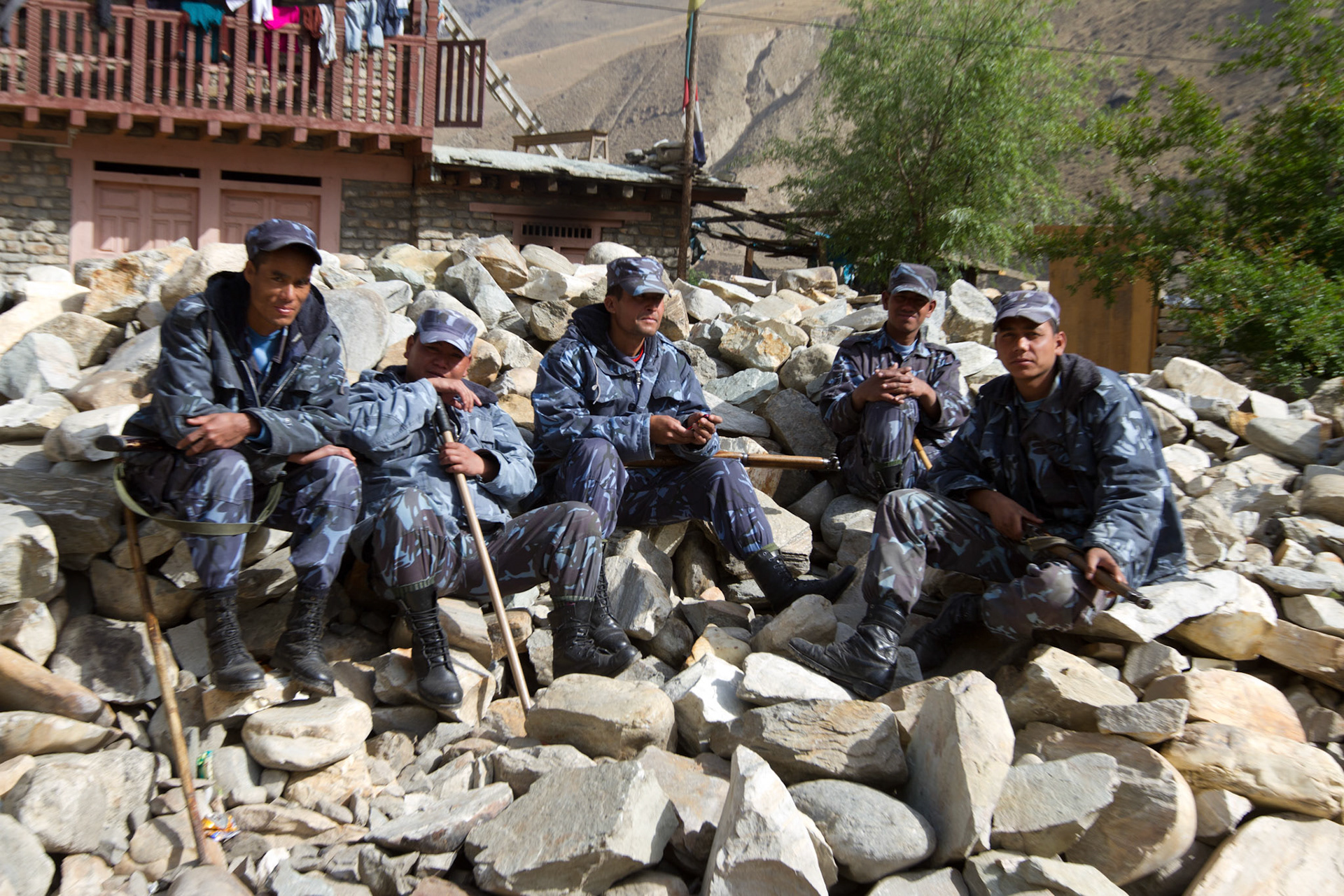 Armed police sit on rocks at the edge of Dunai. The Karnali area of Nepal in the mid western hills and along the Chinese border is one of the most food insecure regions in Asia. The World Food Program estimate 75% of the children in the district have stunted growth and up to 50% are malnourished. With an expanding population and drying climate the challenge ahead is significant. 24/04/2011, Dunai, Nepal.