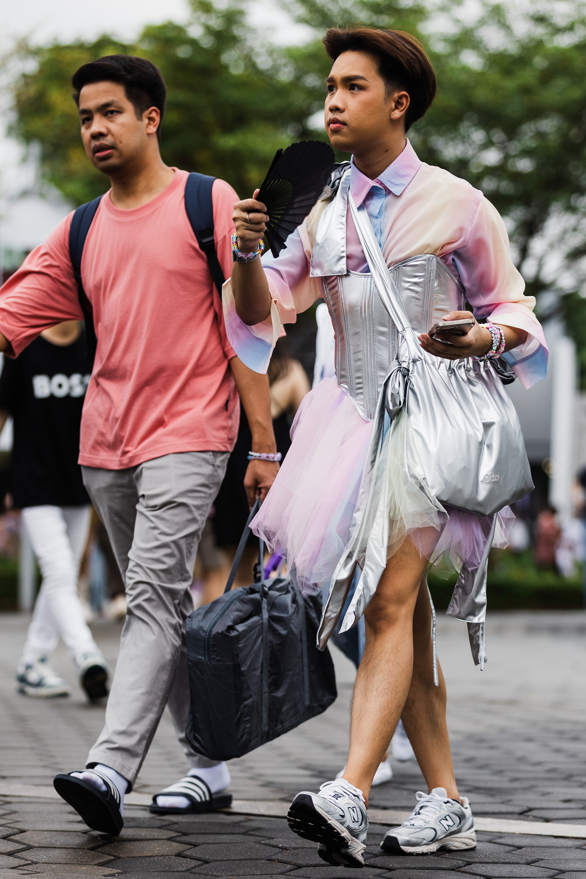Environmental study of concert-goers in soft pastel hues, documenting the quiet anticipation and human friction of the crowd before the high-intensity spectacle. Atmospheric fidelity (空気感) of the National Stadium exterior. Captured Actually.