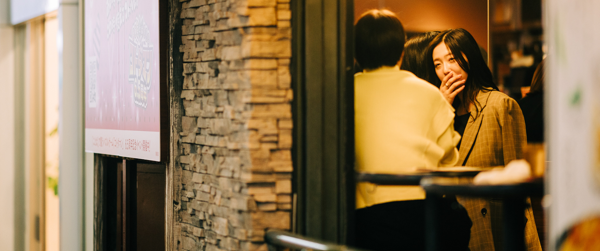 Voyeuristic street photography captured through a stone doorway frame, featuring a woman in a blazer walking down a traditional Japanese street.