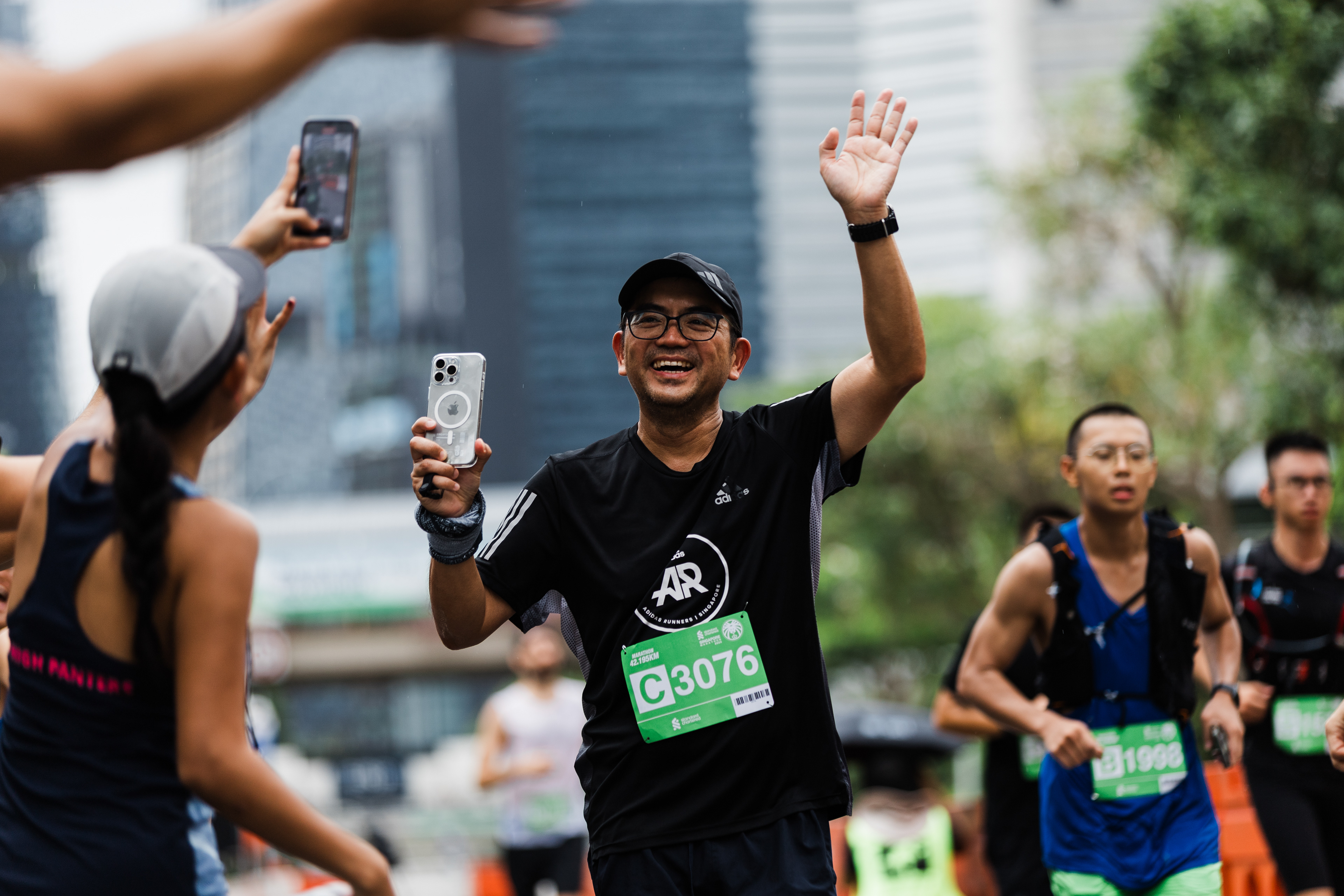 Cinematic high-fidelity documentation of a marathon runner engaging with the crowd; street-level unit-still capturing authentic human joy and urban athletic energy against a blurred cityscape.