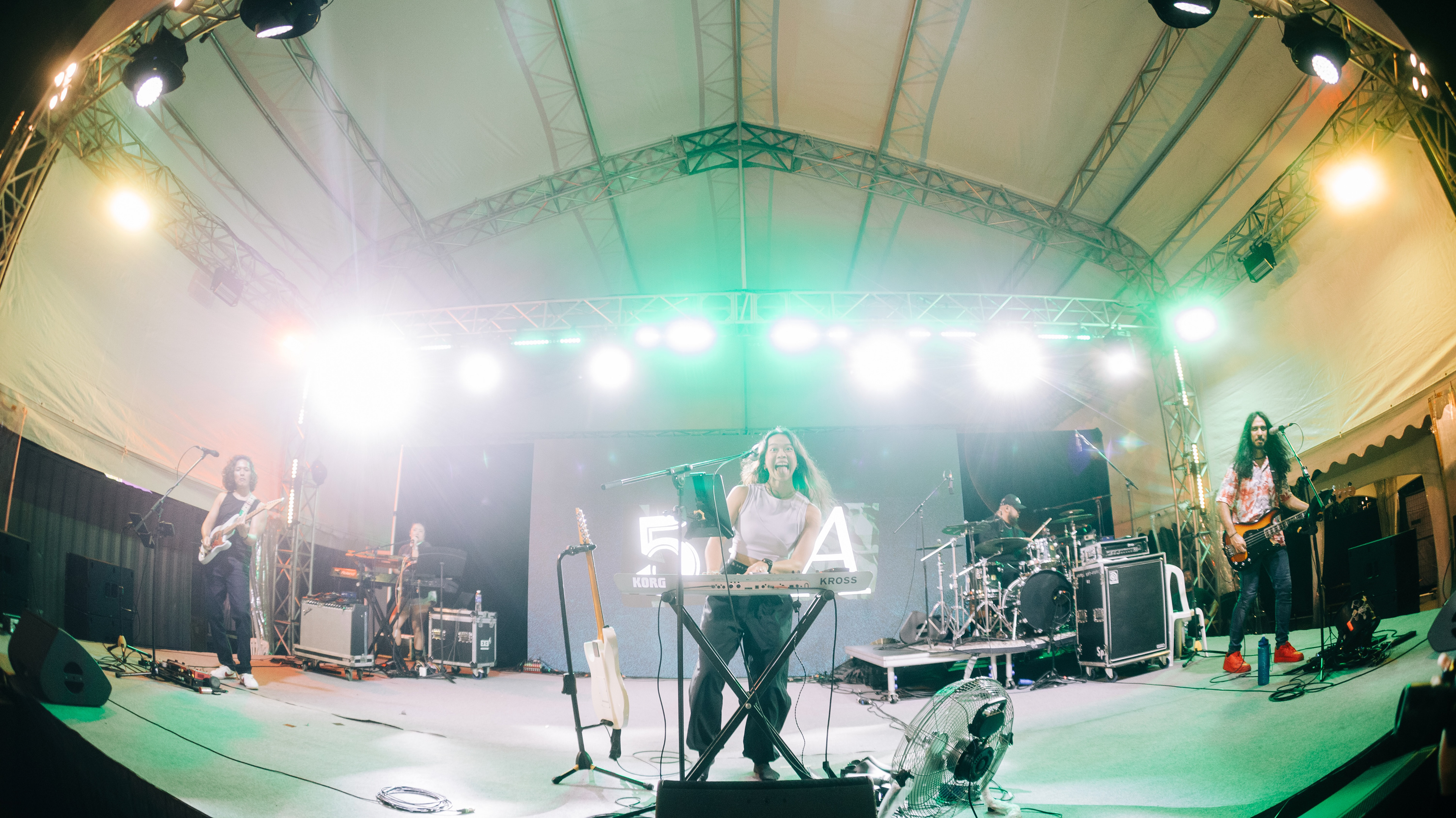 Wide-angle fish-eye perspective of indie band SA53 performing live under full stage lighting rig at the GastroBeats festival venue in Singapore.