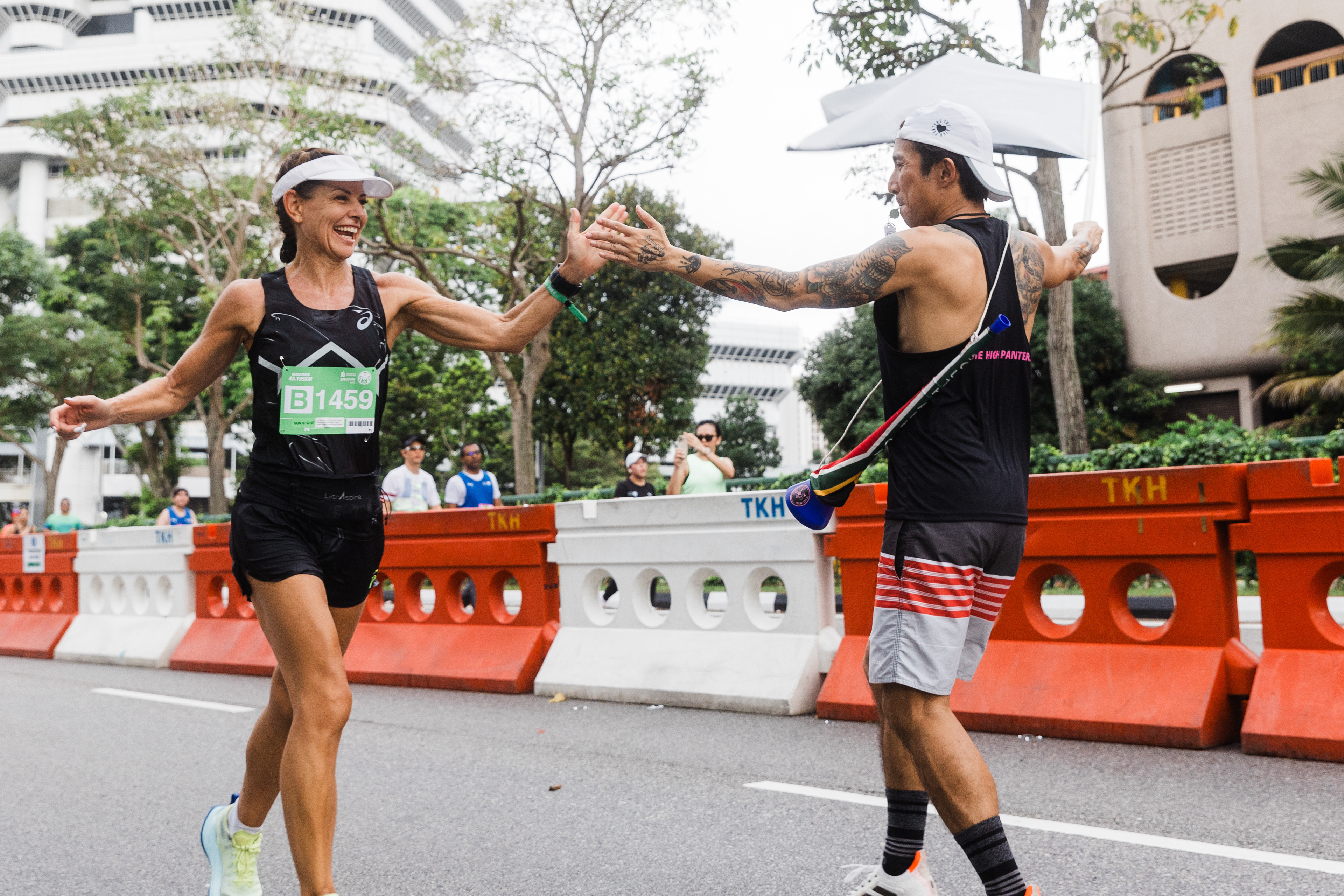 Cinematic unit-still capturing a high-five between an urban marathon runner and a spectator; high-fidelity documentation of community support and peak athletic energy in an urban environment.