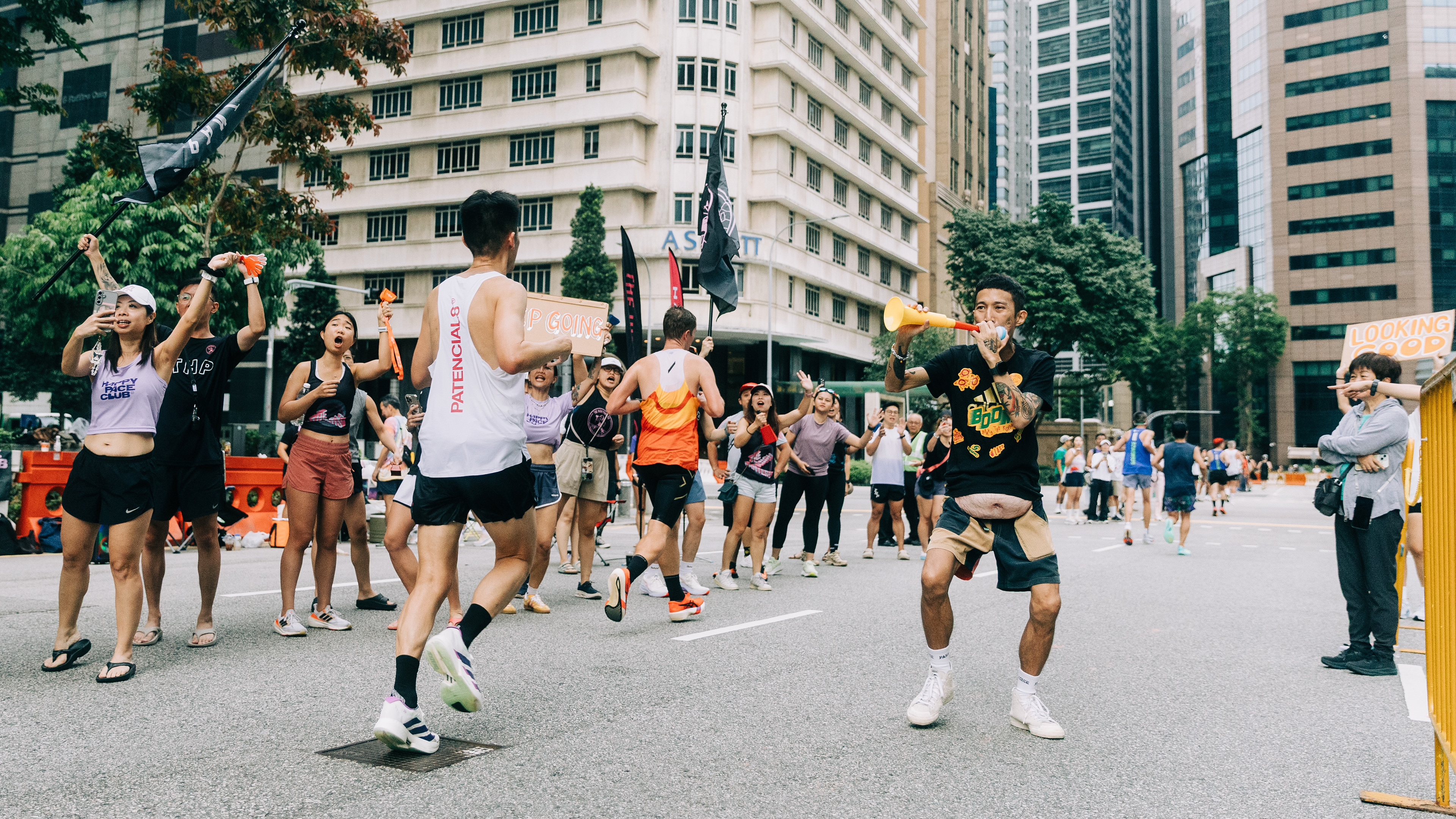 Cinematic unit-still capturing high-velocity event energy; street-level documentation of an urban marathon with dynamic crowd interaction and industrial city backdrops