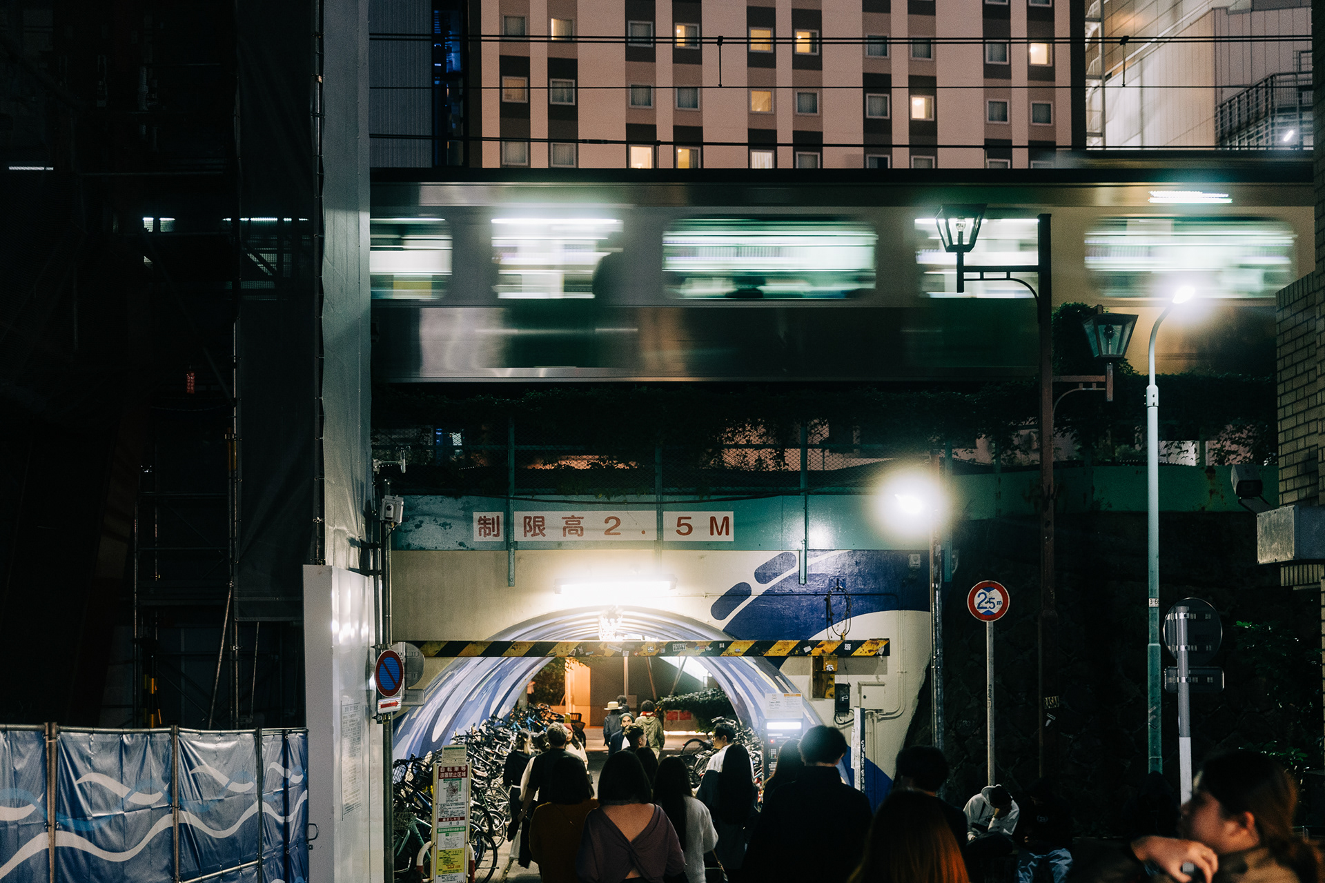 Cinematic wide shot of a concrete urban tunnel in Tokyo with a motion-blurred train passing overhead. High-contrast lighting and industrial architectural lines.