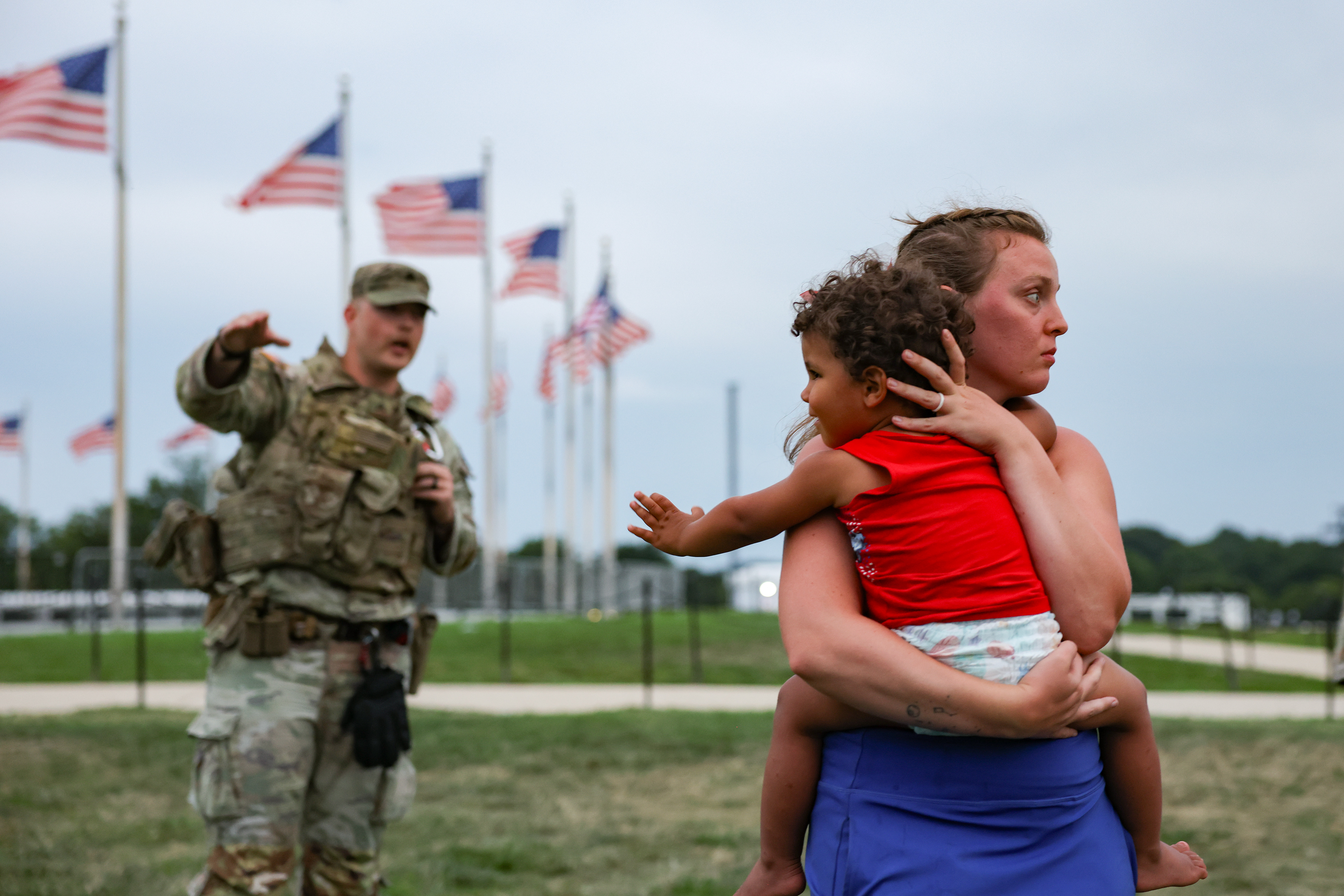 A member of the National Guard enforces an evacuation order of the National Mall as a concerned visitor holds a child on July 4, 2026 in Washington, D.C. (Photo by Tyler M. Andrews/The Washington Post) 
