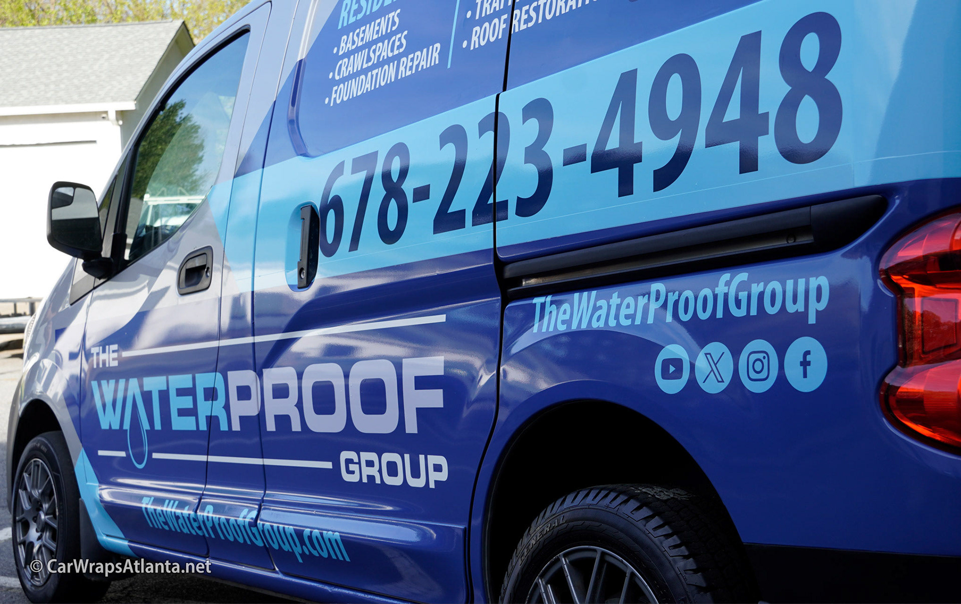 Full view of the custom partial wrap on the Nissan NV200 van demonstrating high visibility in an urban setting.