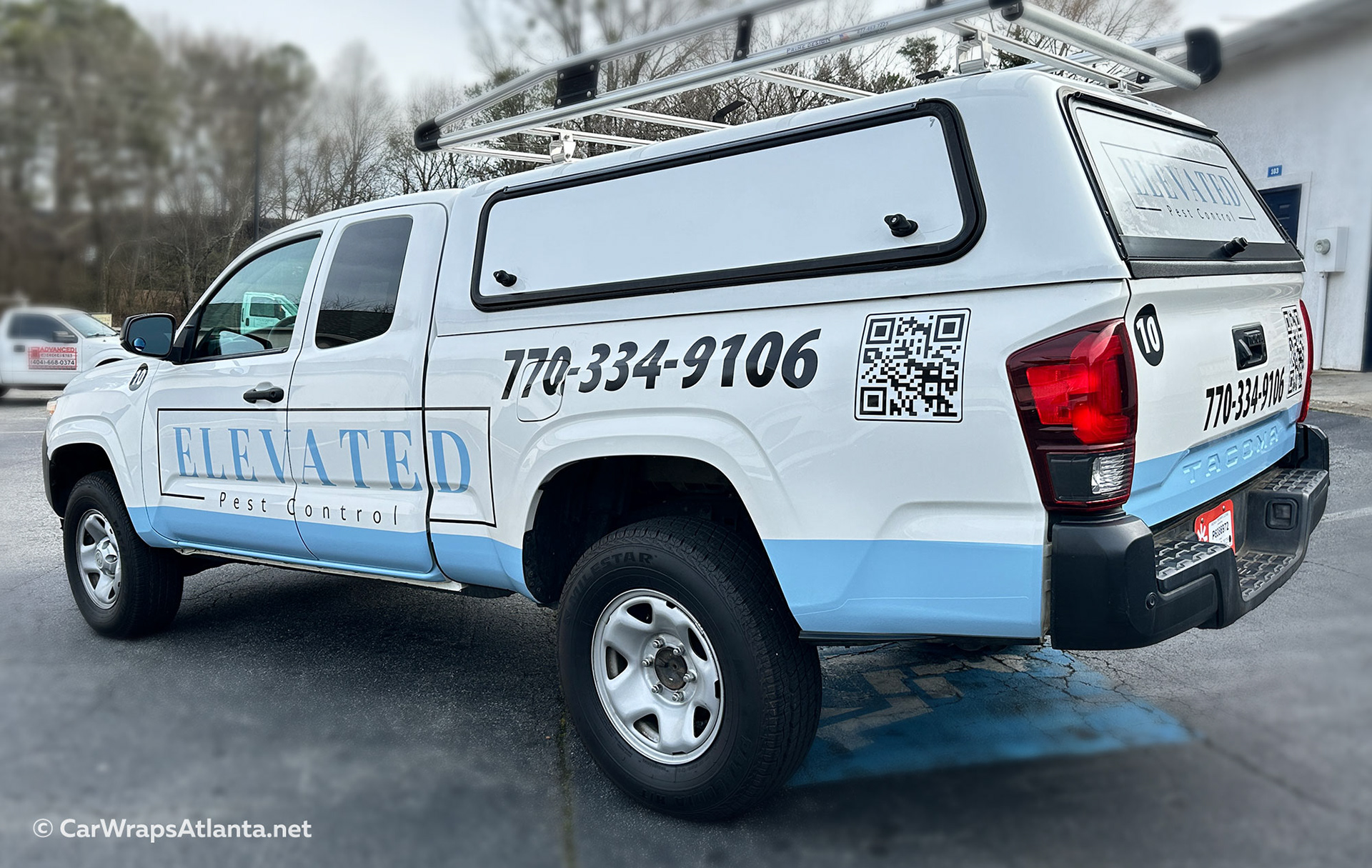 Toyota Tacoma with pest control spot graphics in Atlanta featuring bold logo and contact details on door and tailgate.