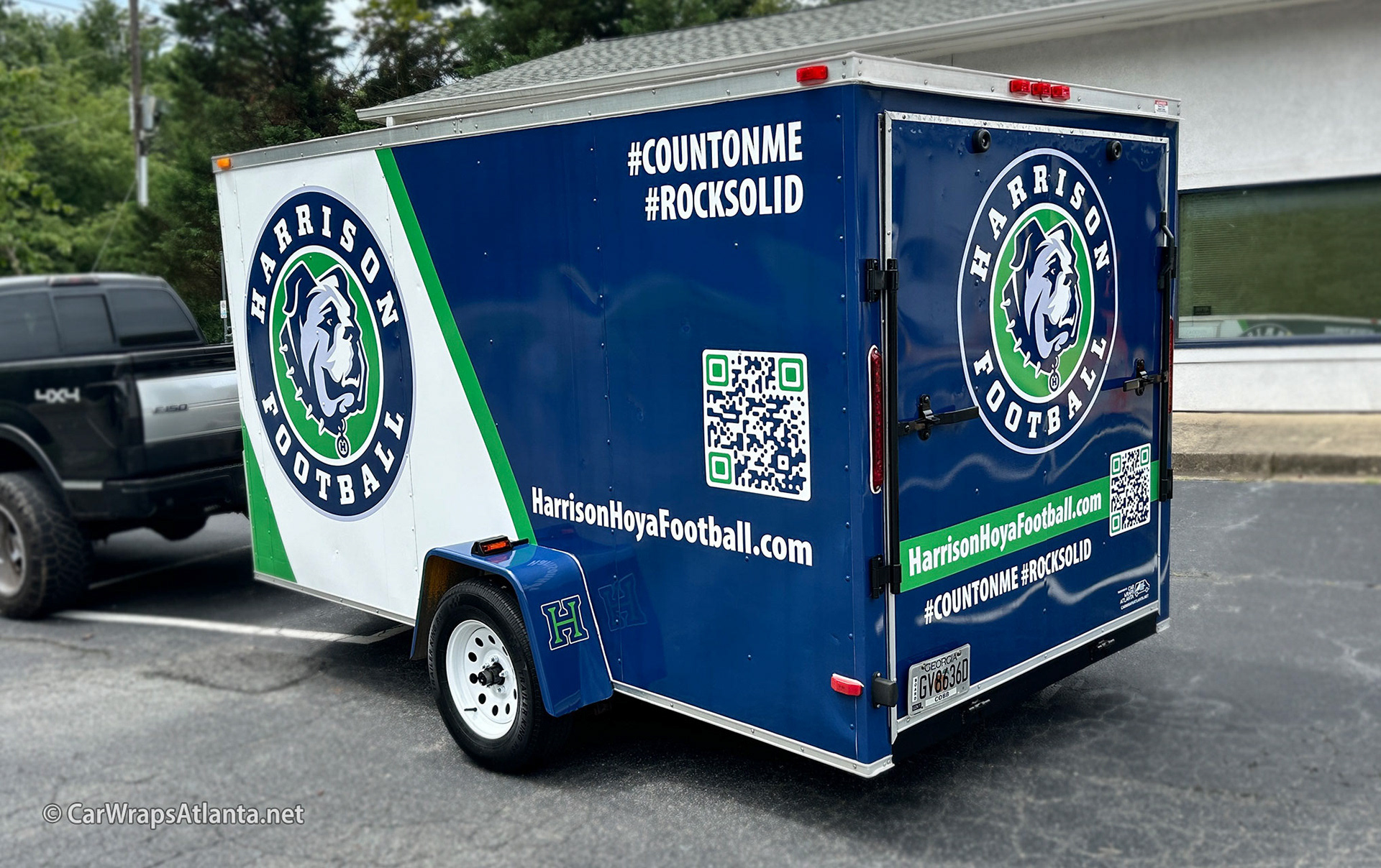 Full trailer wrap for Harrison Hoya Football parked at a high school athletics event in Kennesaw.