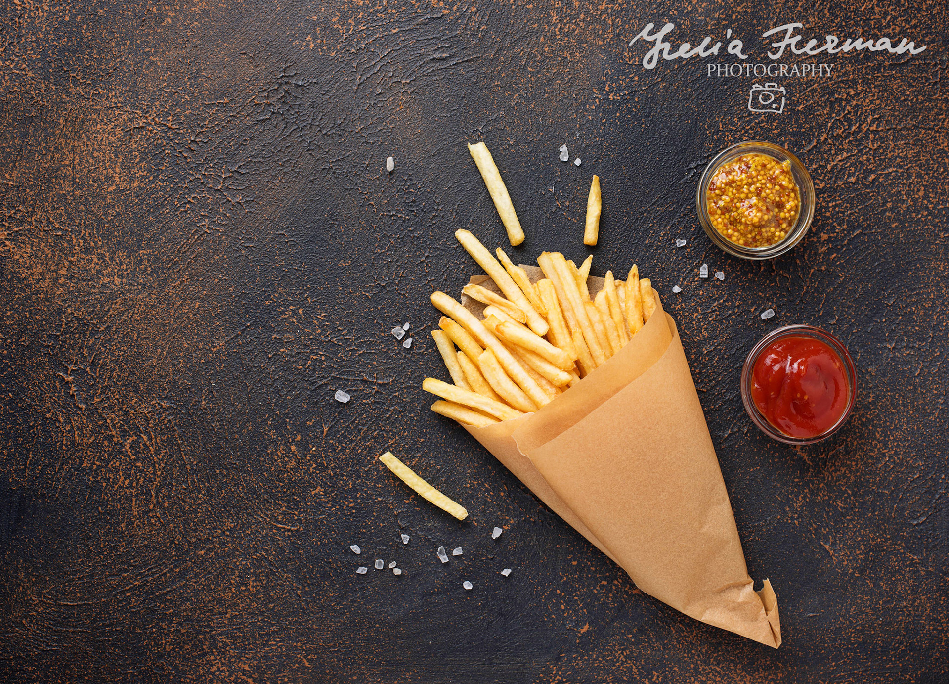 French fries in a paper bag with sauces. Top view