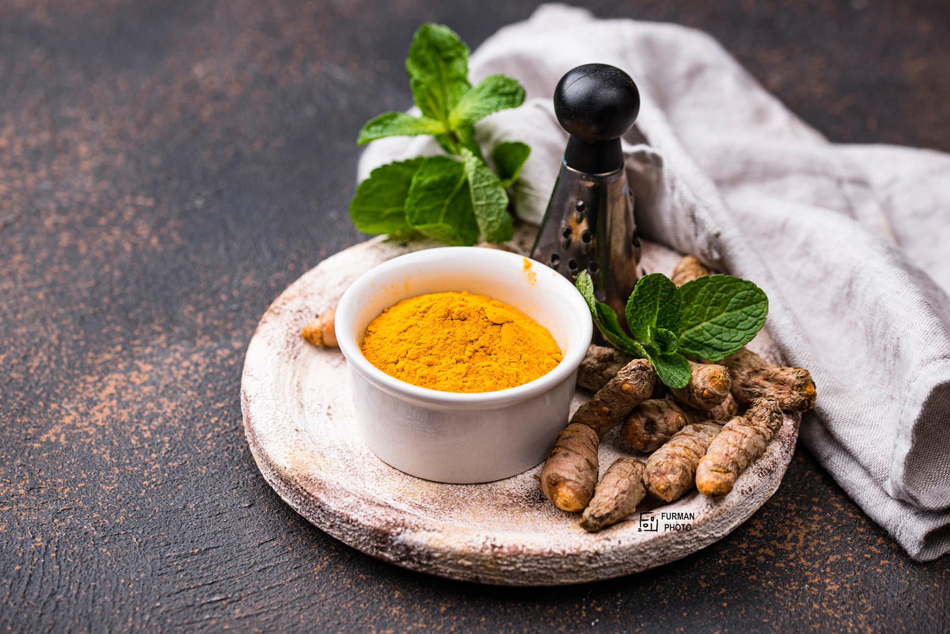 Turmeric powder in bowl and fresh curcuma root