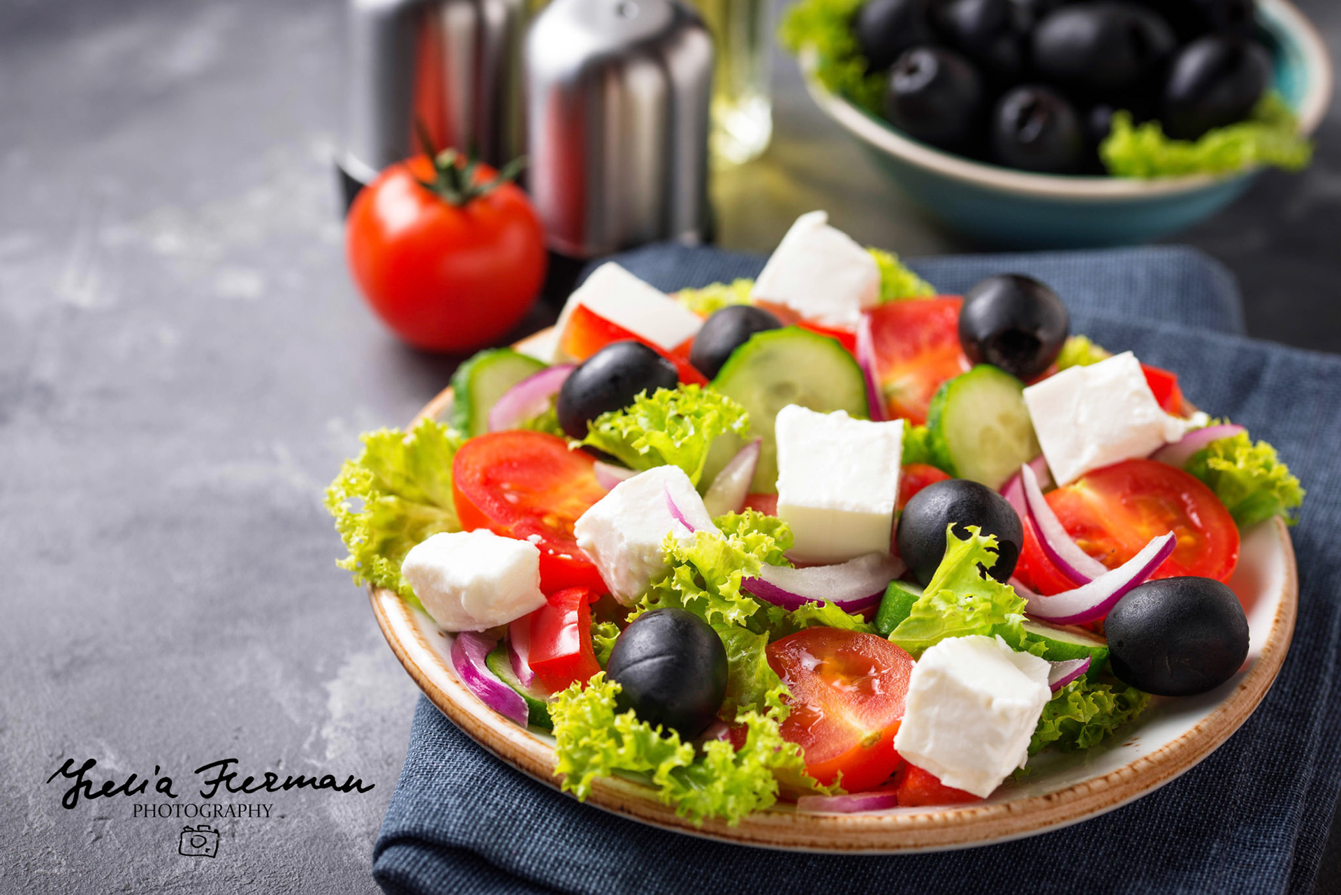 Traditional Greek salad with feta, olives and vegetables on light background
