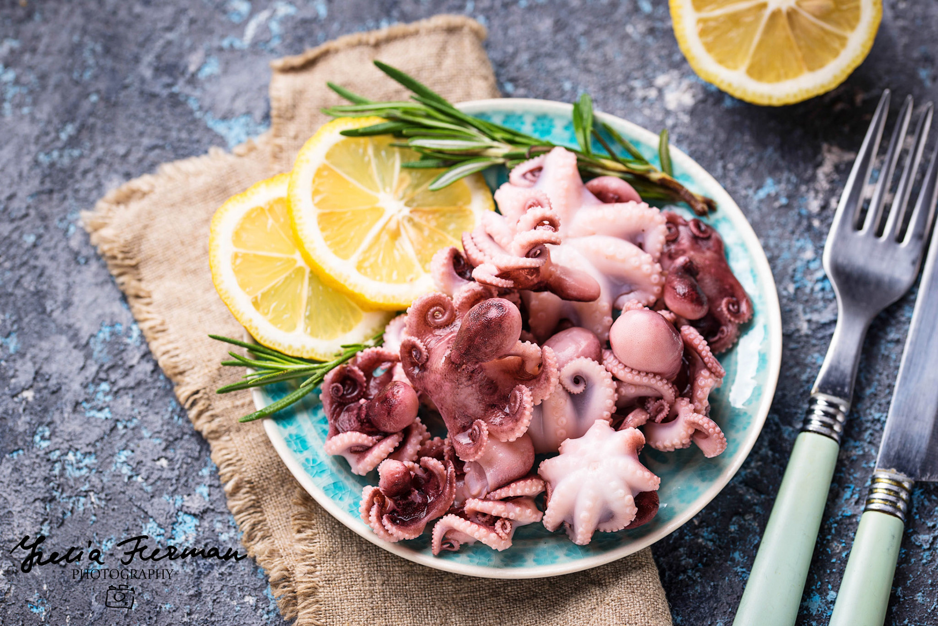 Baby octopus in plate with lemon and rosemary. Selective focus