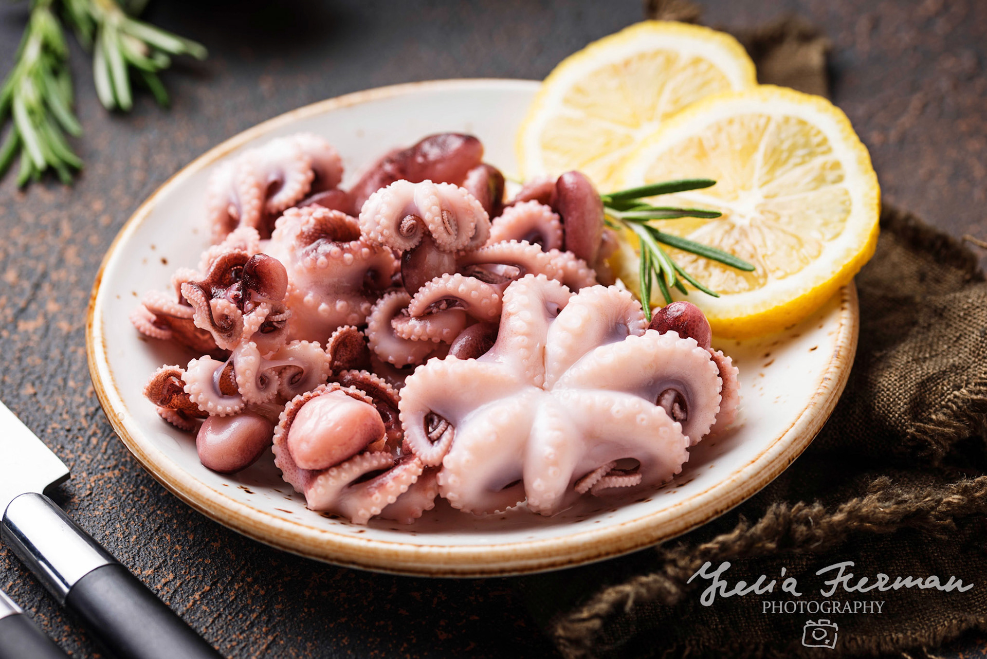 Baby octopus in plate with lemon and rosemary. Selective focus