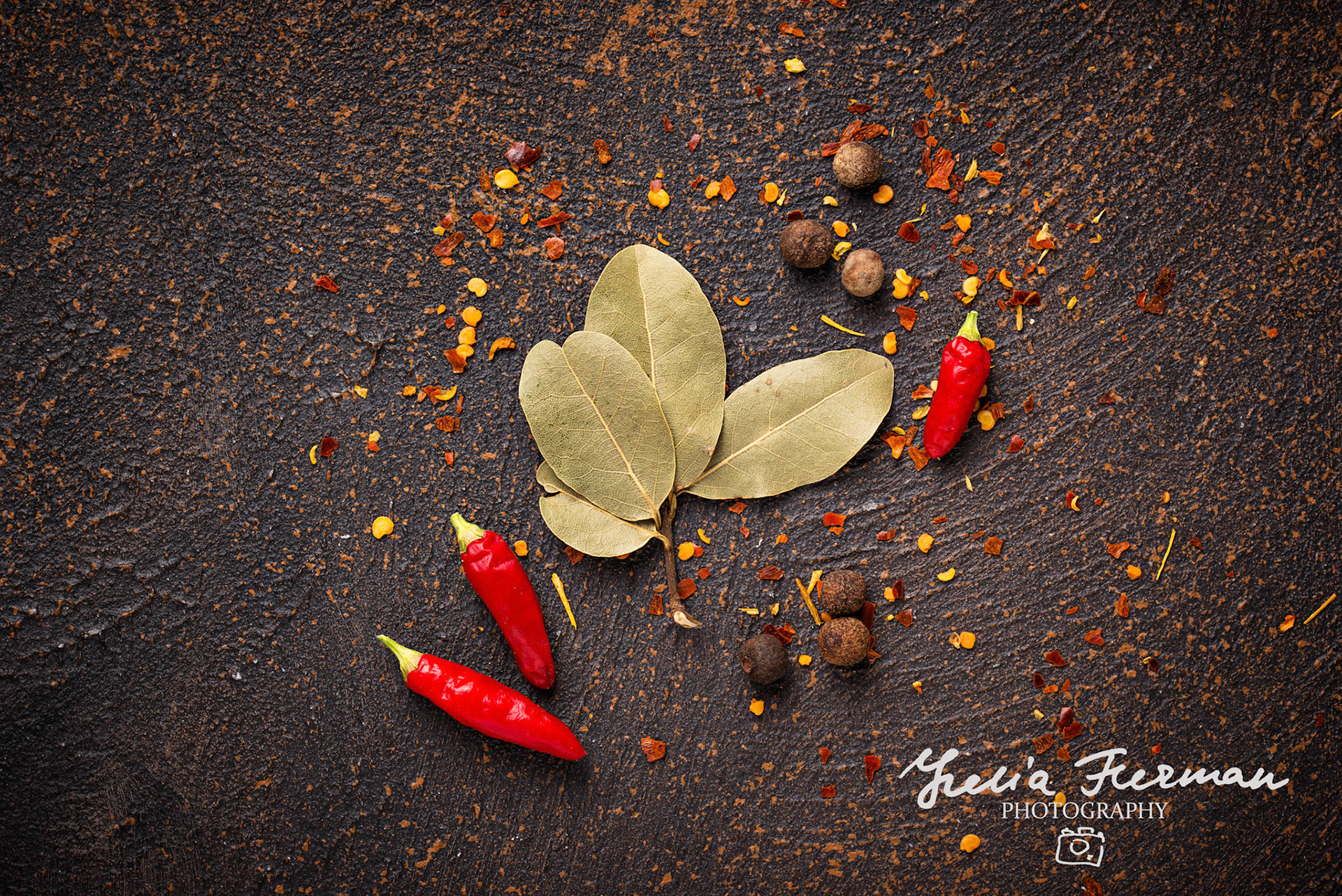 Red chilli pepper and bay leaf on rusty background
