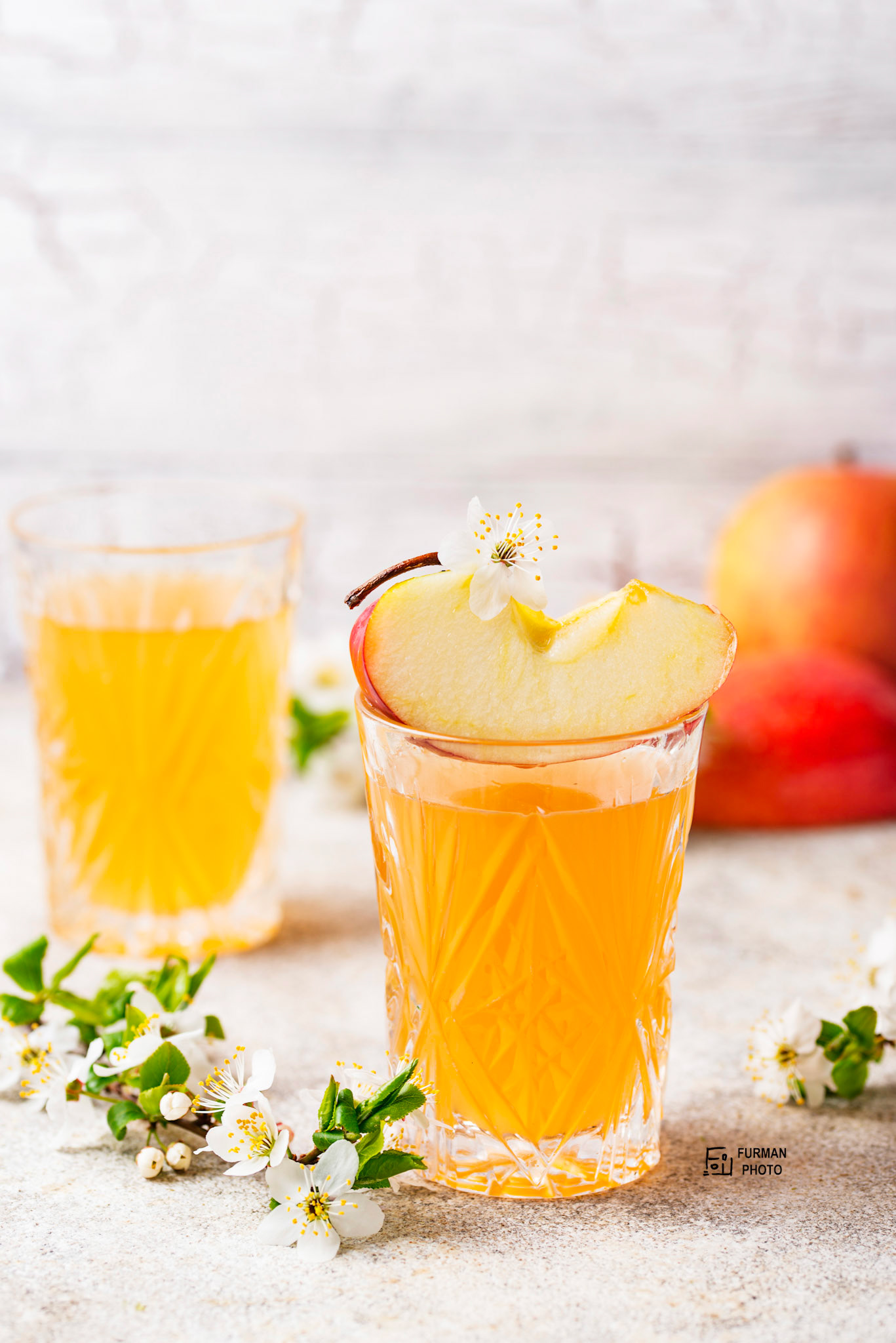 Glasses with fresh apple juice or cider on light background