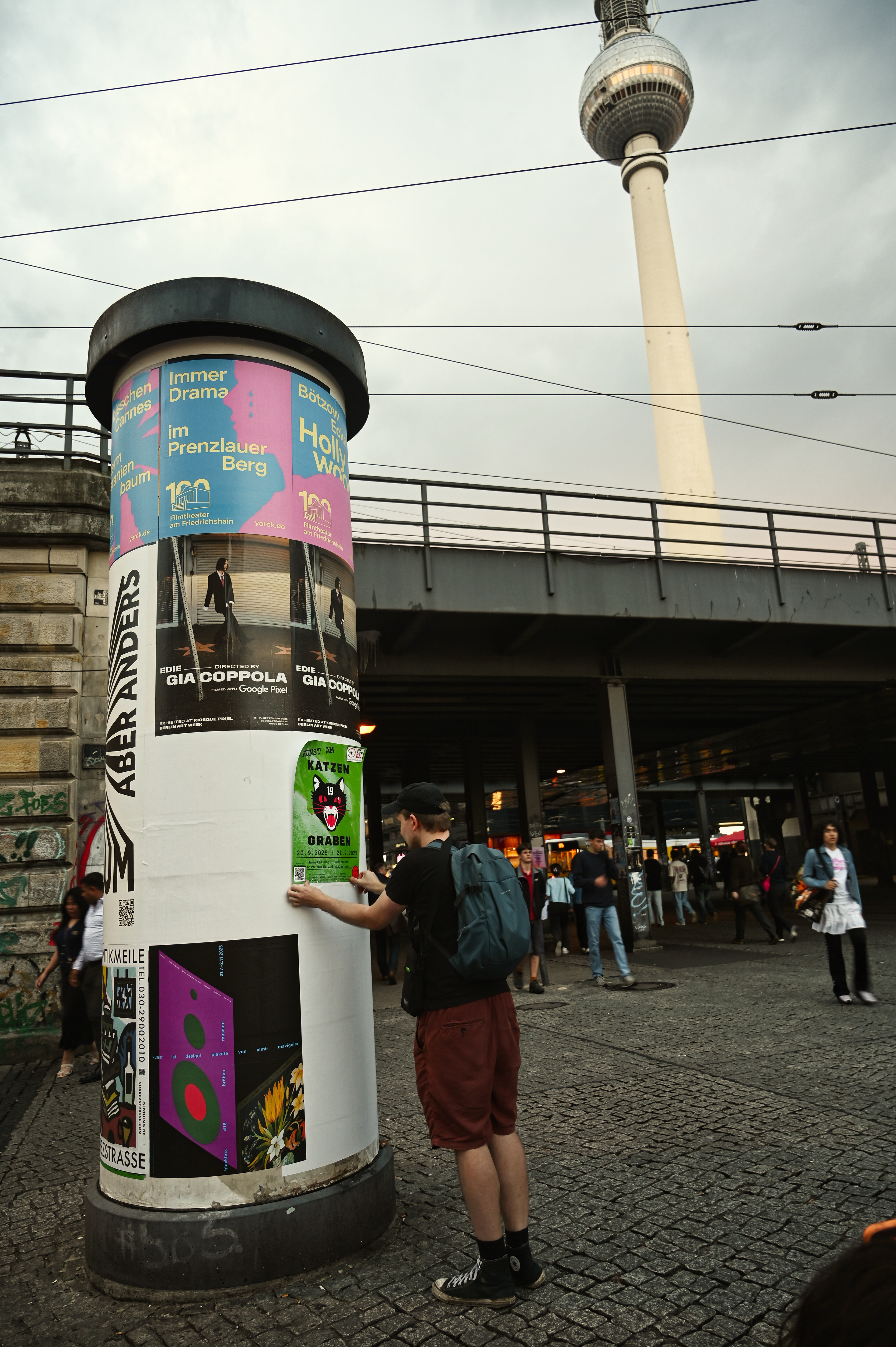 Künstler Rise klebt ein Plakat von KAK am Alexanderplatz Berlin 