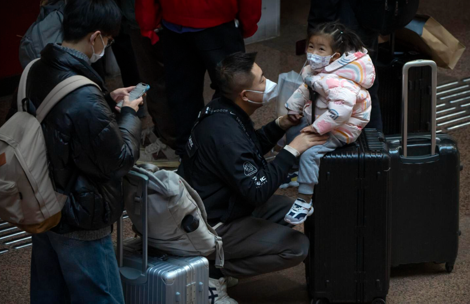 A child sits on a suitcase at Beijing West Railway Station in Beijing, Wednesday, Jan. 18, 2023. China in December lifted its strict "zero-COVID" policy, letting loose a wave of pent-up travel desire, particularly around China's most important time for family gatherings, referred to in China as the Spring Festival, that may be the only time in the year when urban workers return to their hometowns. (Mark Schiefelbein/The Associated Press)