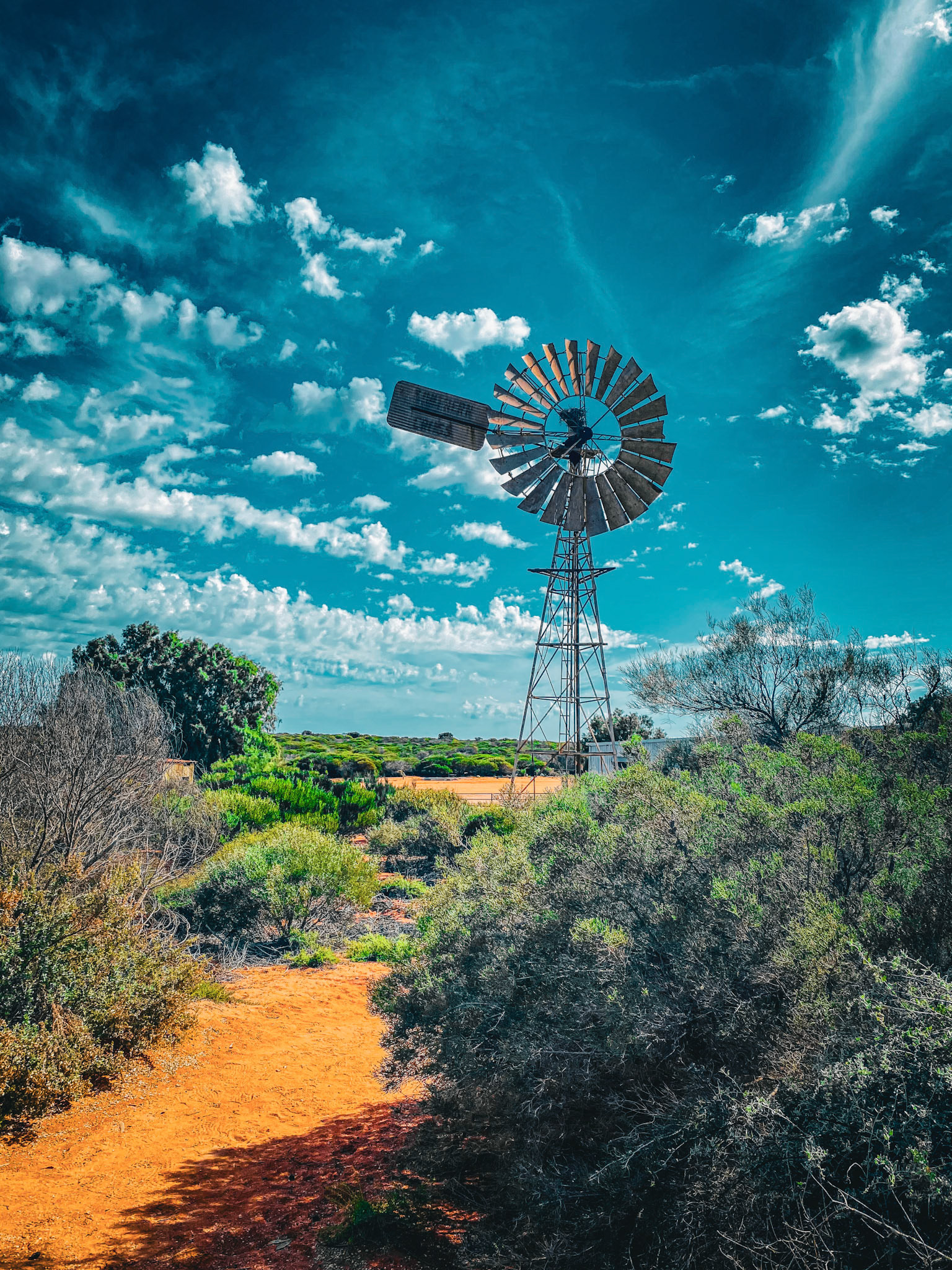 A vintage windmill symbolizes resilience and history in a rugged landscape, showcasing nature's enduring spirit and agricultural heritage.