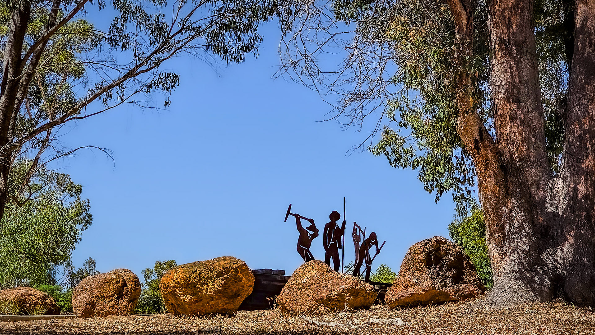 This artwork features silhouettes of workers laboring in mining, set outdoors under a clear blue sky, highlighting themes of heritage.
