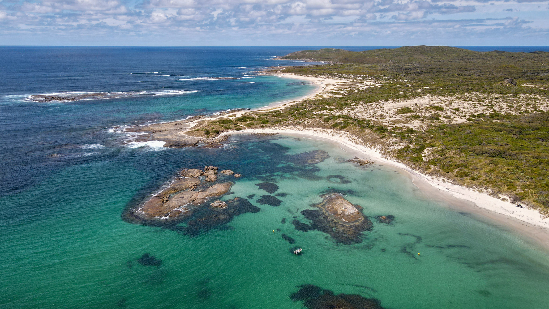 Explore a breathtaking aerial view of a serene coastline, featuring turquoise waters, sandy beaches, and lush green hills.
