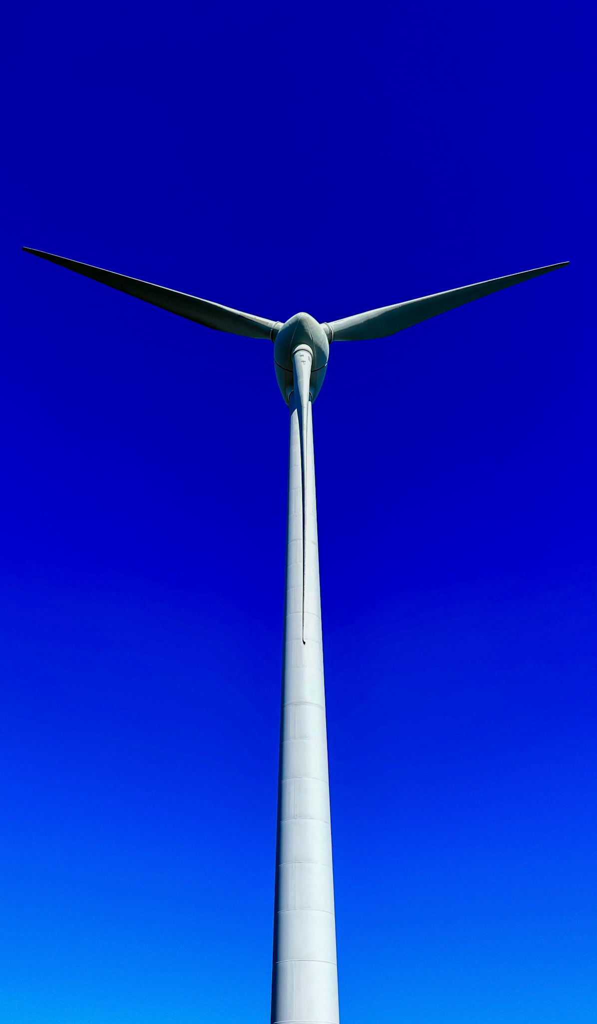 A wind turbine towers against a clear blue sky, representing renewable energy and sustainability in a powerful, serene manner.