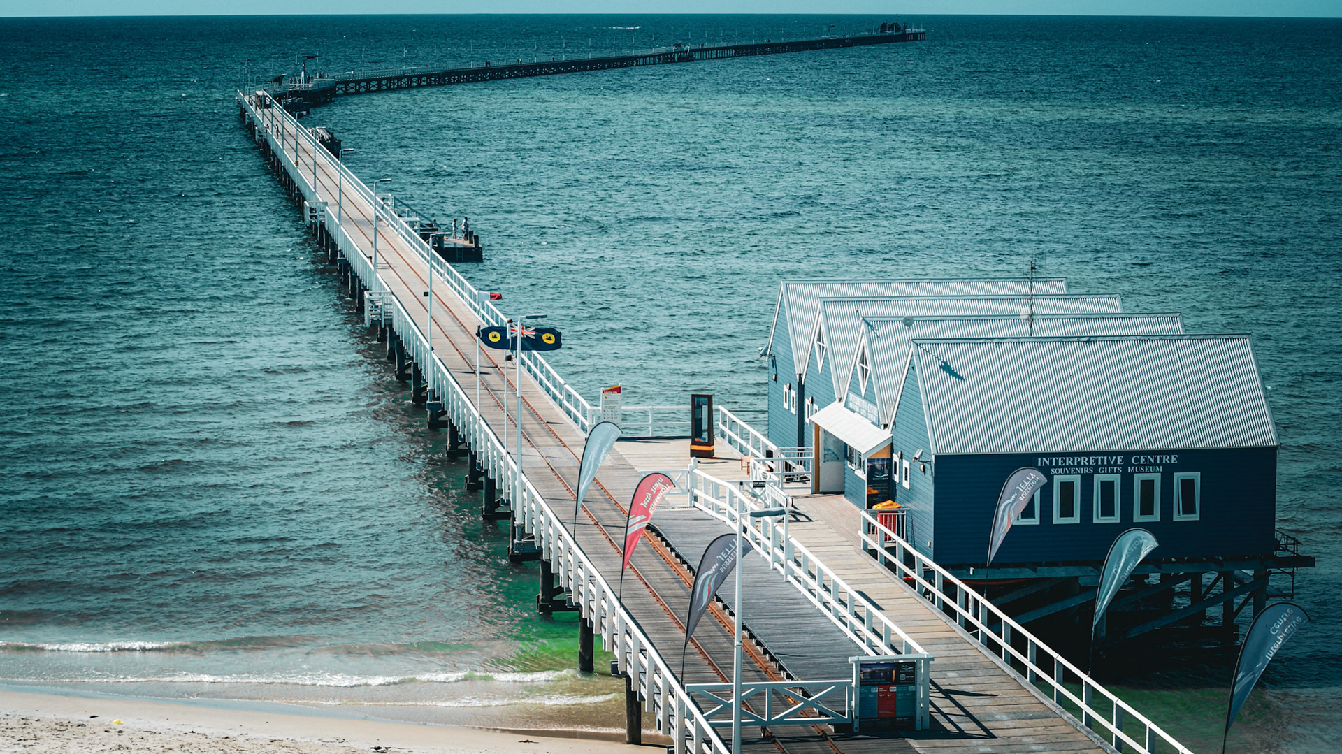 A long wooden pier extends into the calm ocean, surrounded by charming buildings. This tranquil scene captures the essence of seaside leisure.