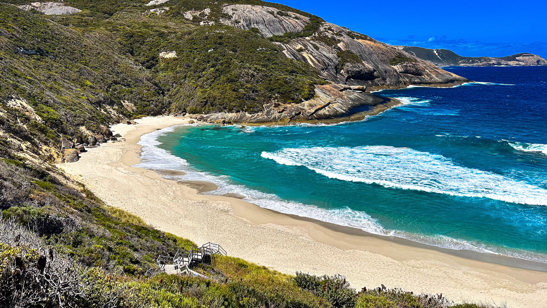 This aerial view showcases a secluded beach, surrounded by cliffs and turquoise waters, embodying tranquility and natural beauty.
