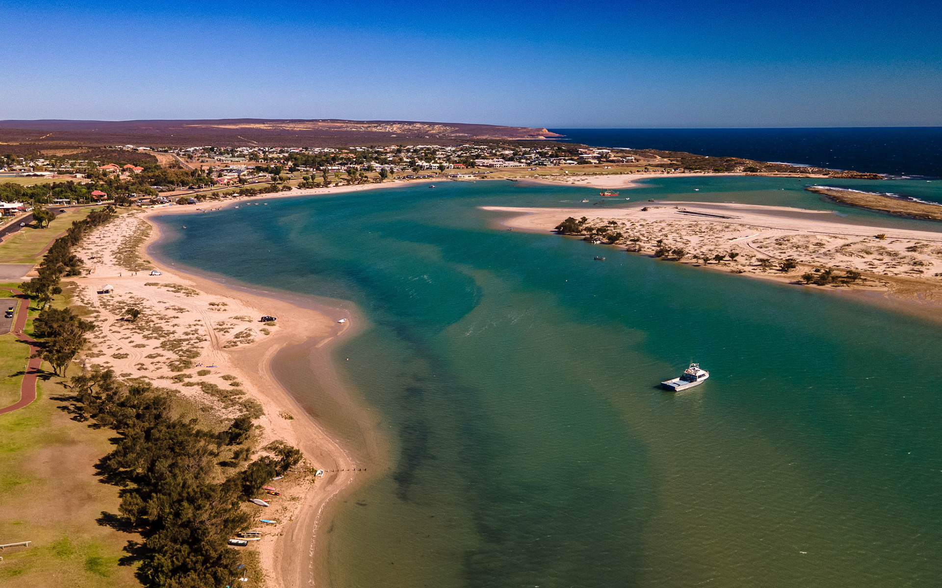 Experience the serenity of a coastal town with a sandy beach, clear waters, and a peaceful atmosphere perfect for vacation.