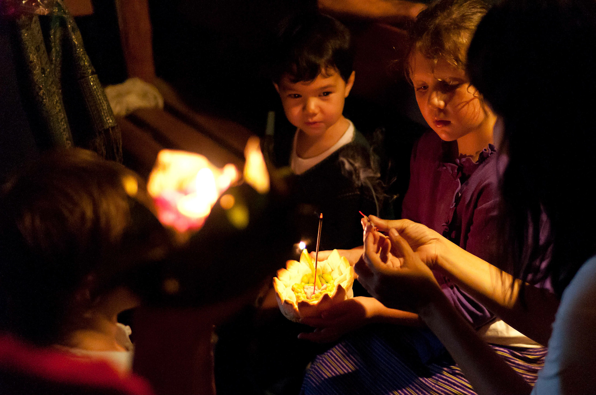 Lighting krathongs before placing them on the water during the Loy Krathong fesitval