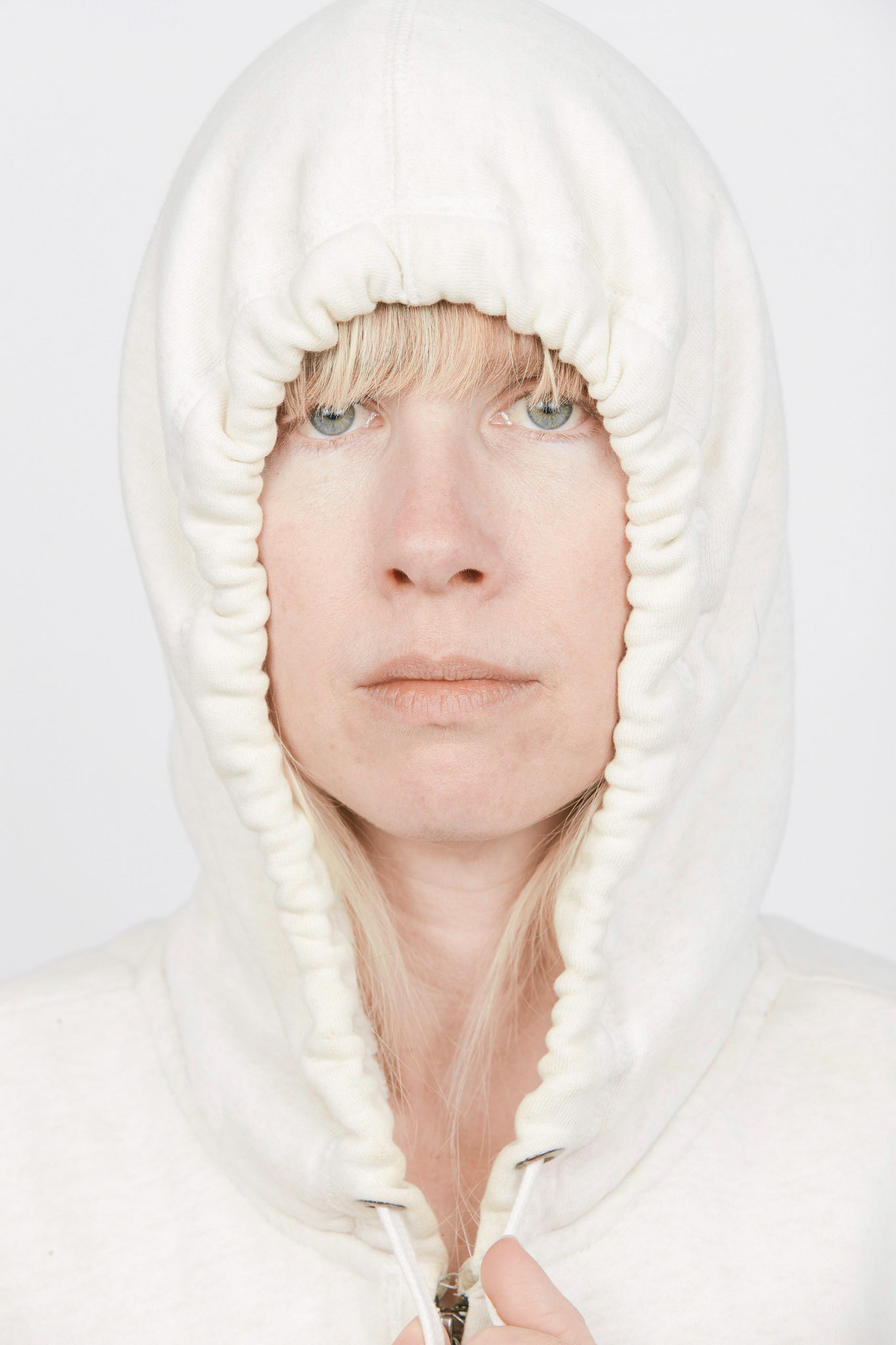 Studio portrait of a white woman with blonde hair wearing a hoodie, white background