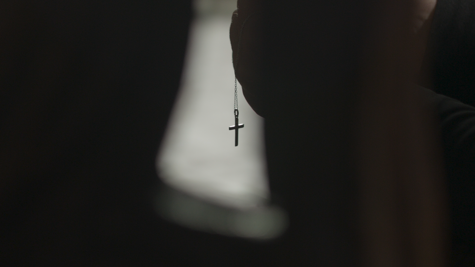 Close up on a priest holding a cross necklace.