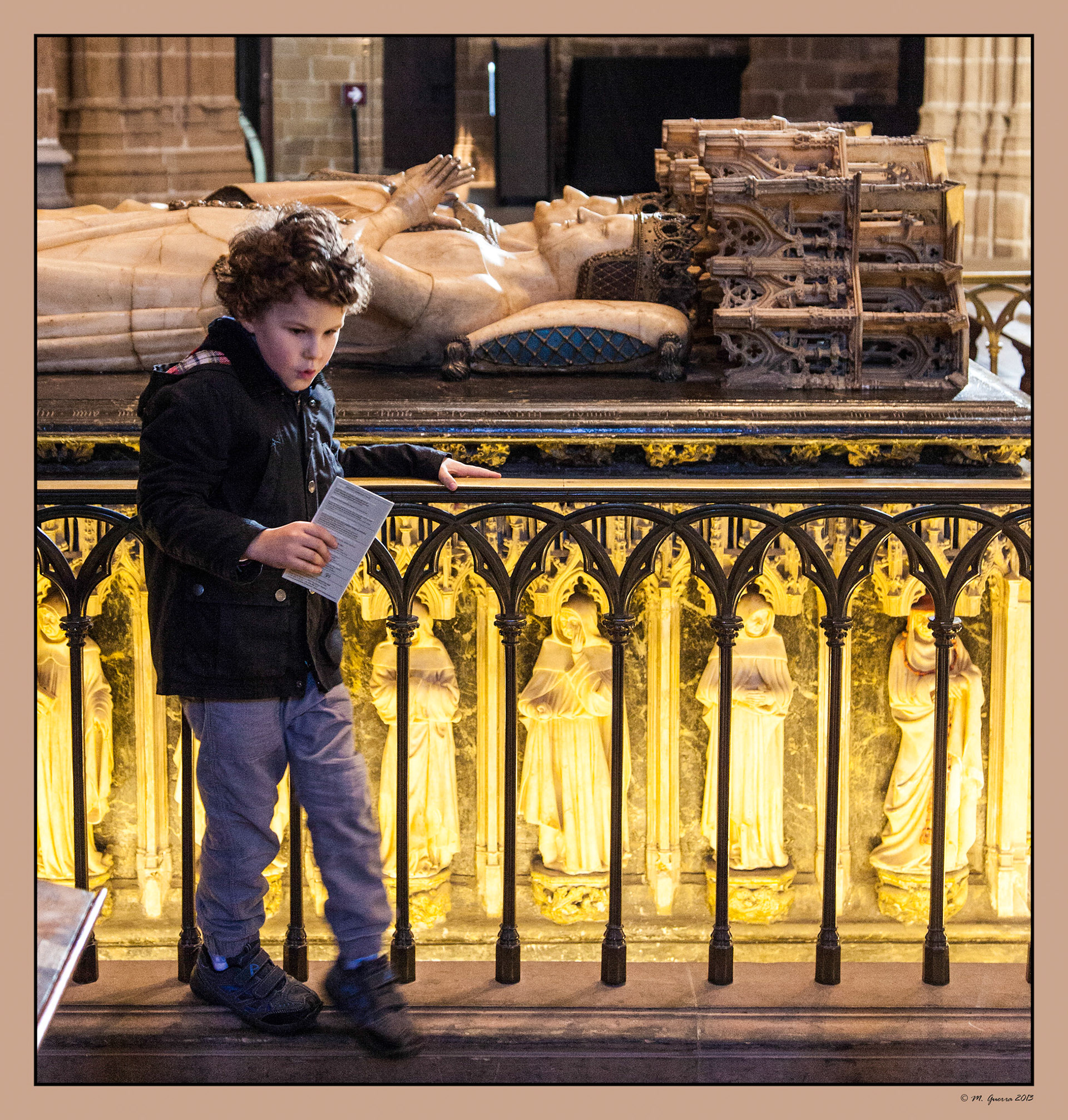 Un niño con un folleto y un bolígrafo al lado de la tumba de los Reyes de Navarra en la Catedral de Pamplona. Ampliar