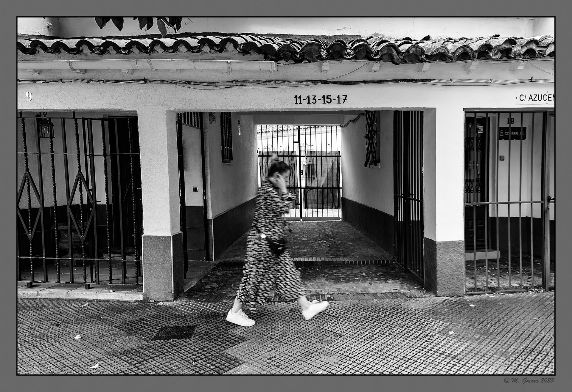 Mujer pasando por delante de un Portal de acceso a un grupo de casas antiguas en Alcalá de Henares un día de lluvia. 100ASA