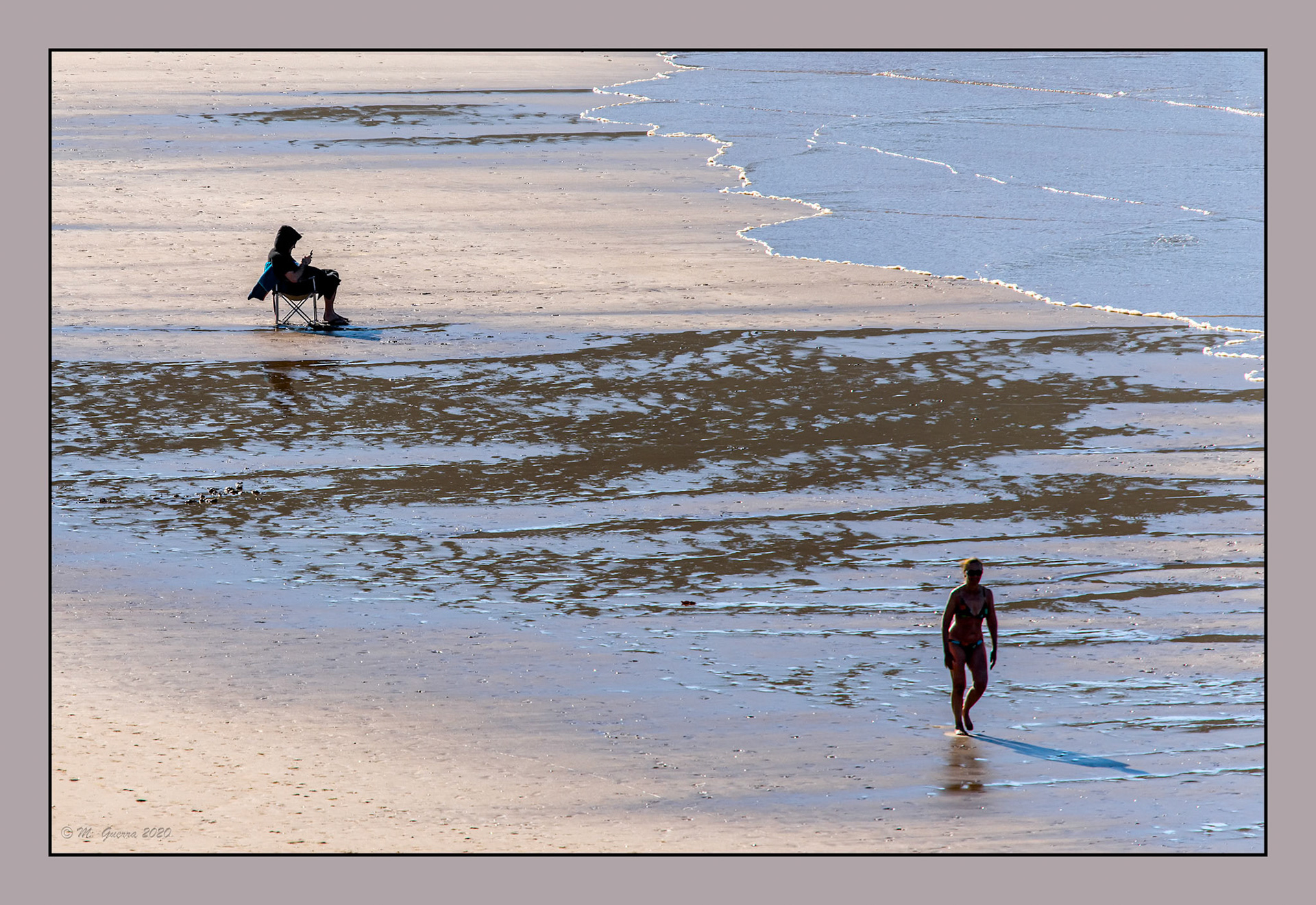 Persona sentada en una silla en la playa de Ribadesella. Ampliar
