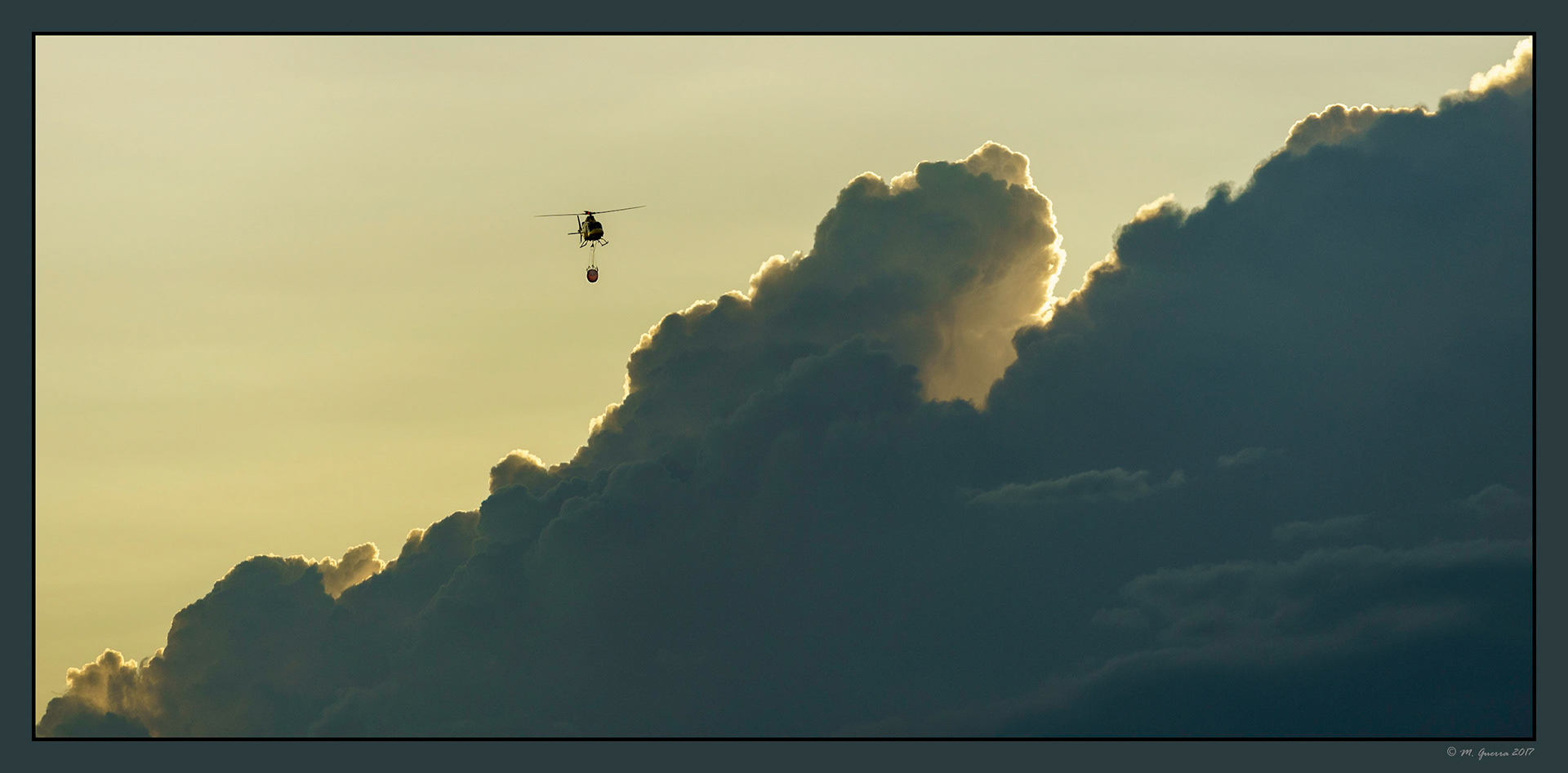 Helicóptero con bolsa contra incendios sobre el campo de Muga. Ampliar
