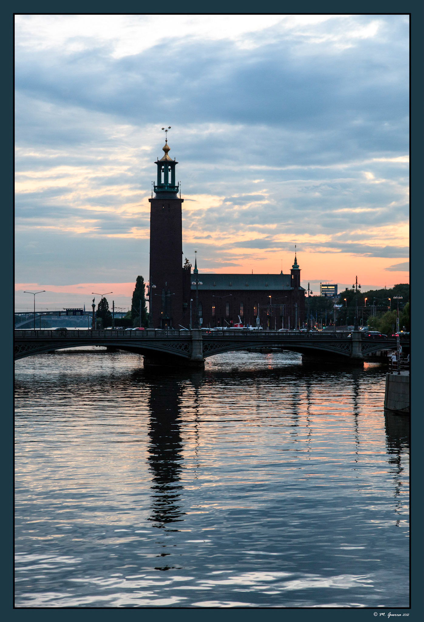 El edificio del Ayuntamiento de Estocolmo reflejado en el agua desde el puente de Riksgatan en el islote de Helgeandsholmen. Ampliar