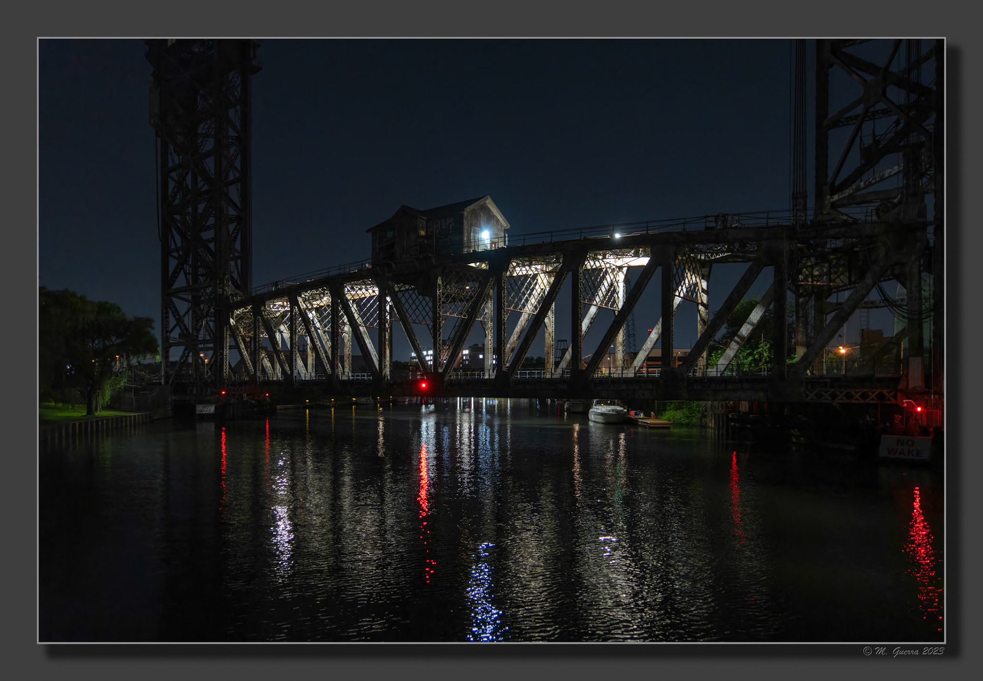 Puente de ferrocarril cruzando el río de noche con dos torres elevadoras en Chicago. 100ASA