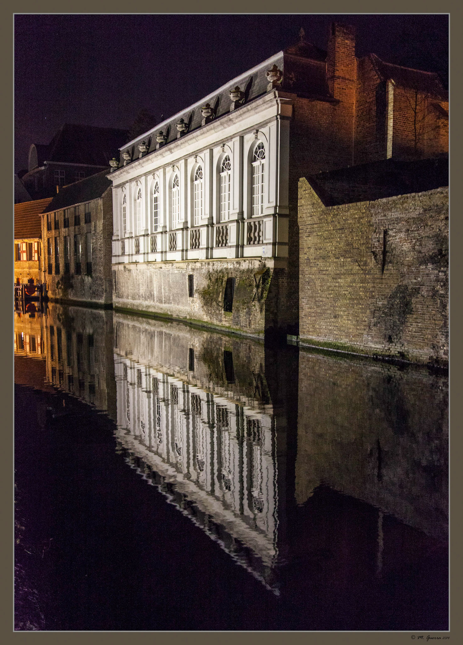 Casas antiguas iluminadas reflejadas en un canal de Brujas. Ampliar