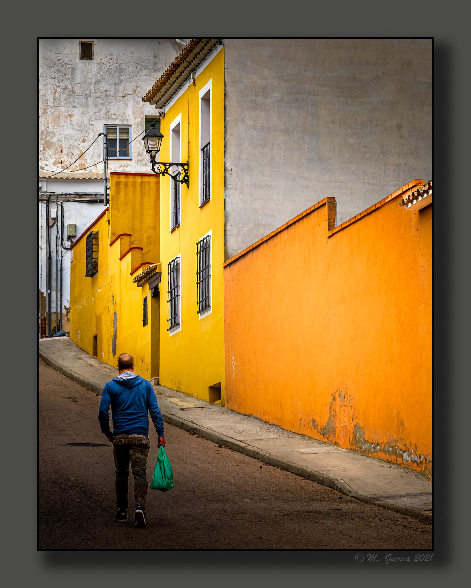 Hombre con una bolsa paseando por una calle de Huete. 100ASA