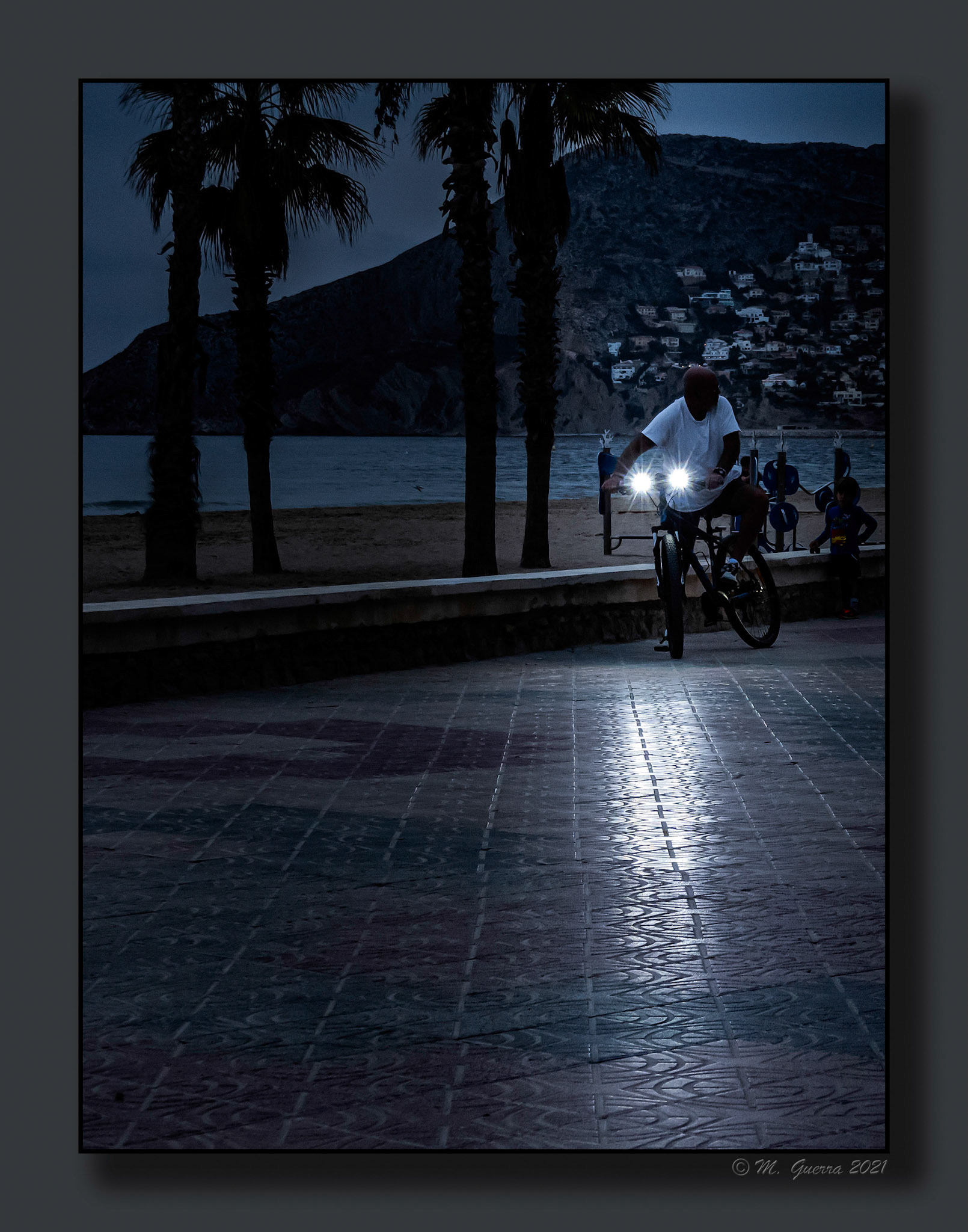 Hombre con una bicicleta con faros en e paseo marítimo de Calpe