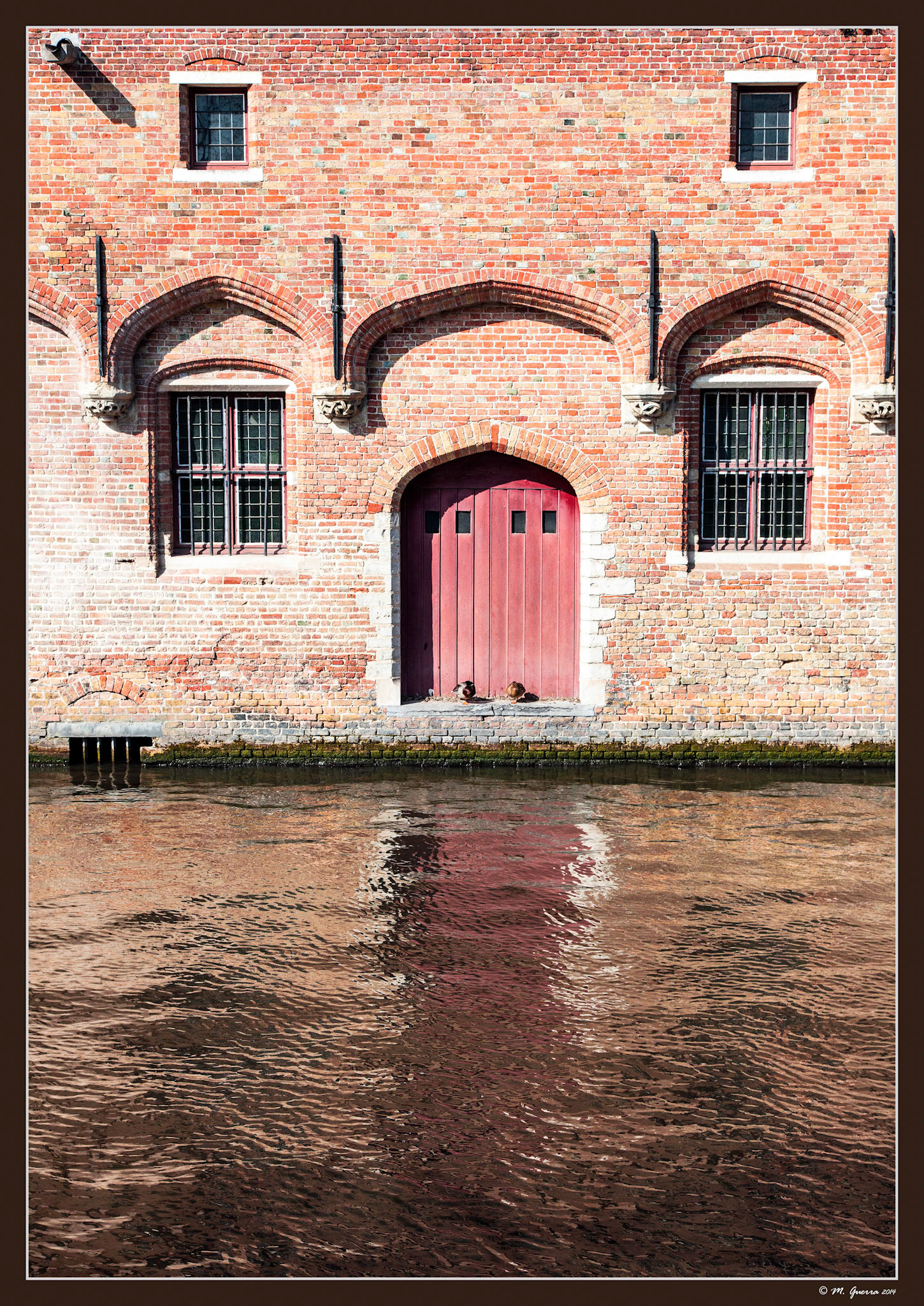 Dos palomas en el dintel de la puerta de una casa a orillas de un canal en Brujas. Ampliar