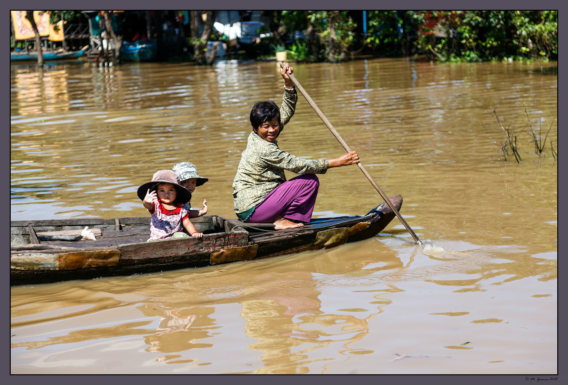 Mujer con dos niños bogando en una barca en el río Siem Reap. Ampliar
