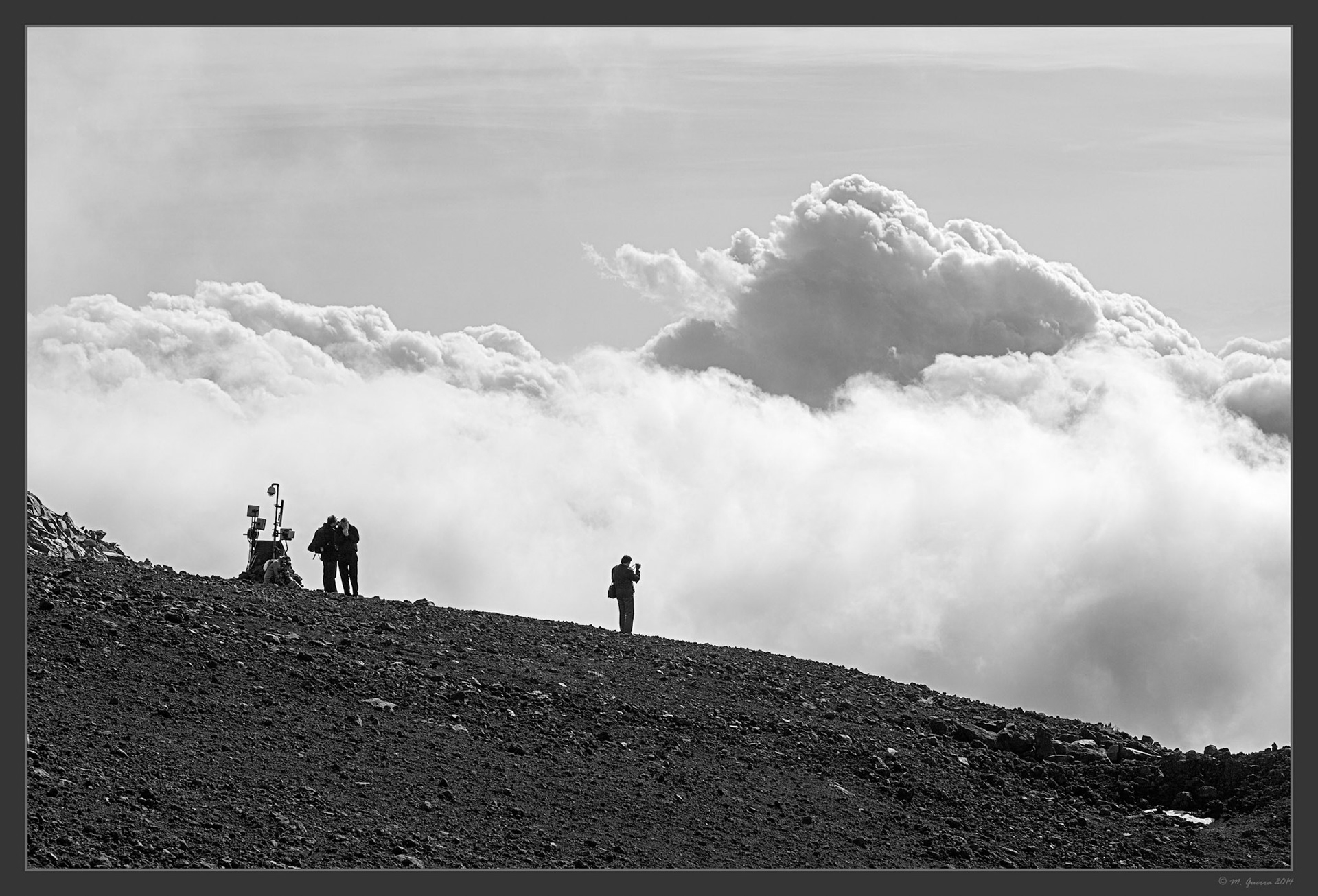 Siluetas recortadas contra un mar de nubes en el Etna. Ampliar