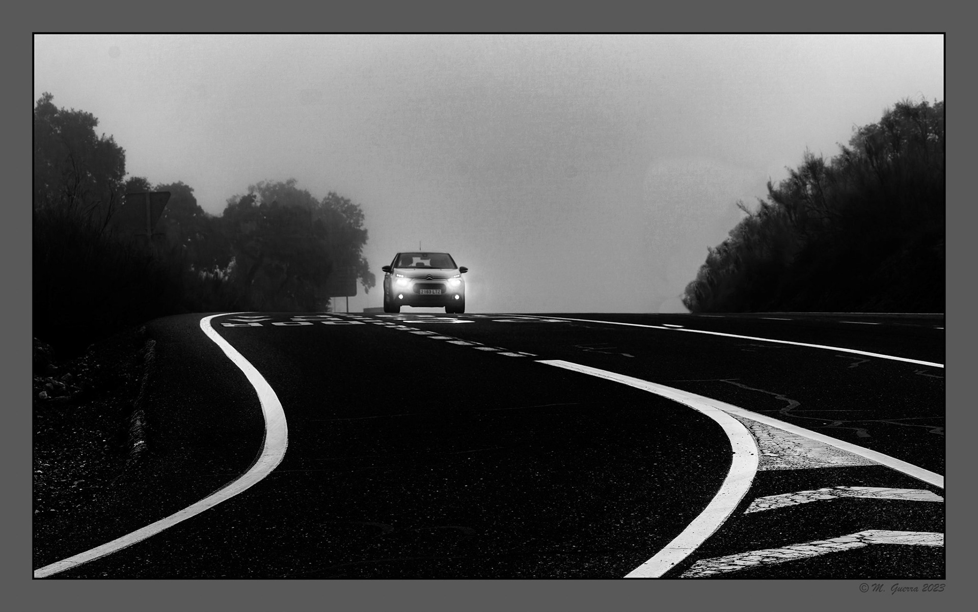 Carretera y coche con las luces encendidas en Toledo un dia de niebla