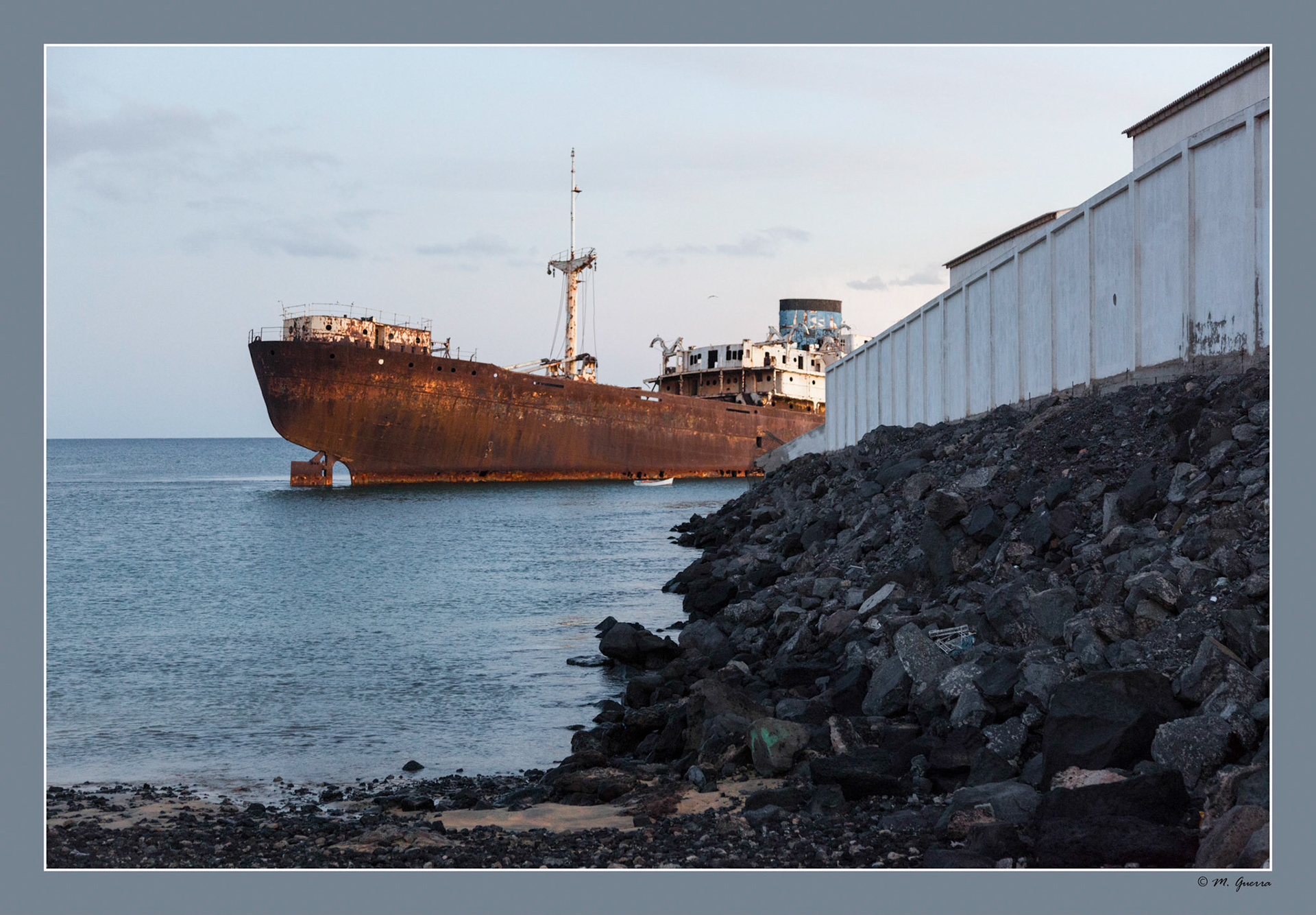 Barco naufragado varado y medio hundido entre una factoría y el comienzo de Costa Teguise en Lanzarote. Ampliar