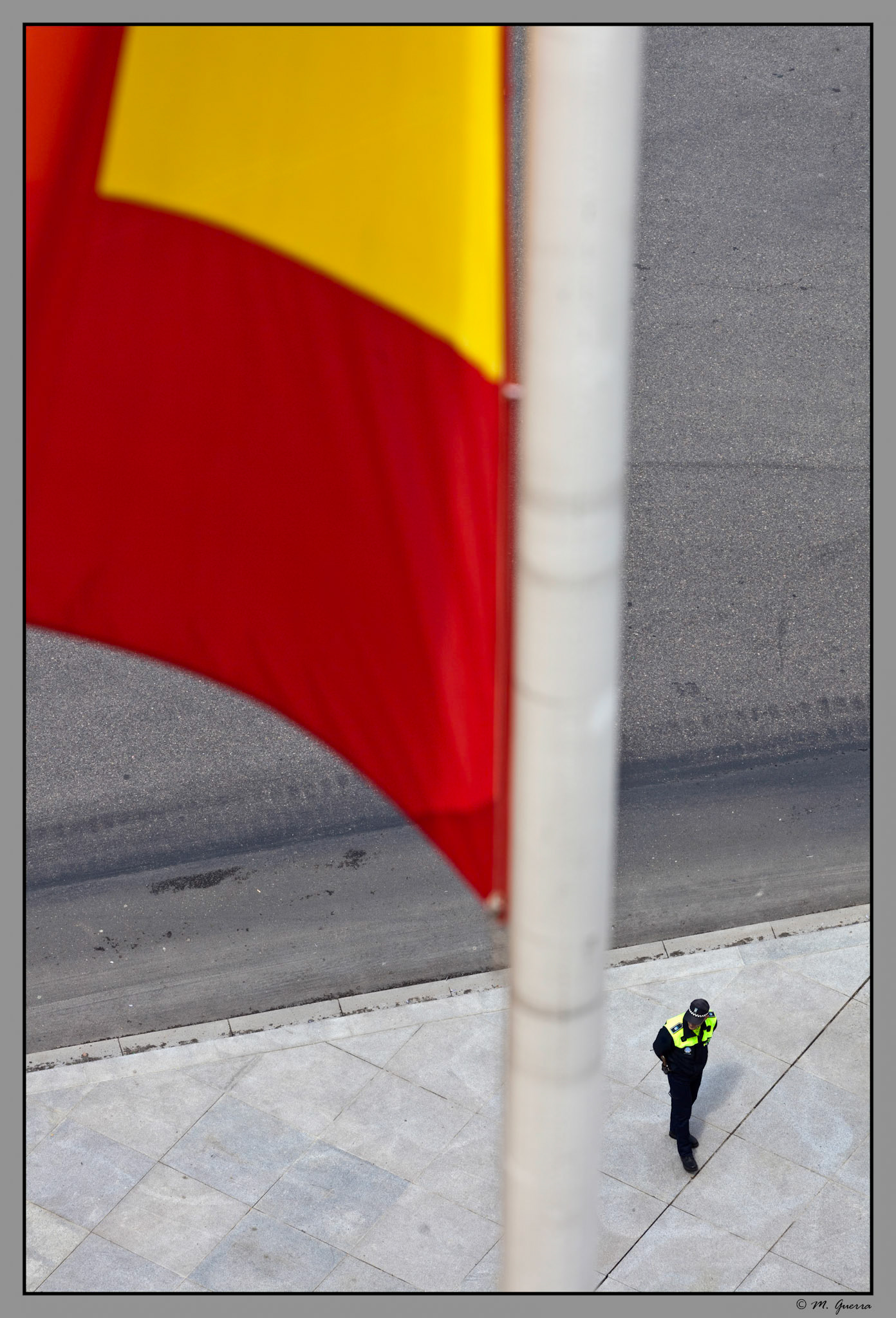 Un Policía Municipal haciendo la ronda el lado del Palacio de Comunicaciones de Madrid, actual sede del Ayuntamiento, después de su remodelación, en un día de jornadas abiertas, con la bandera de españa. Ampliar